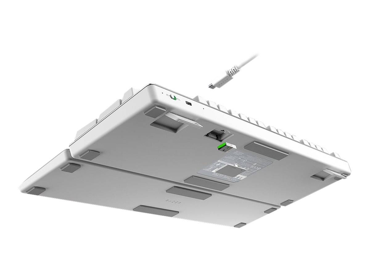 Una tastiera per computer bianca viene mostrata dal basso, un cavo staccabile aleggia sopra di essa. Sul retro ha piedini antiscivolo.