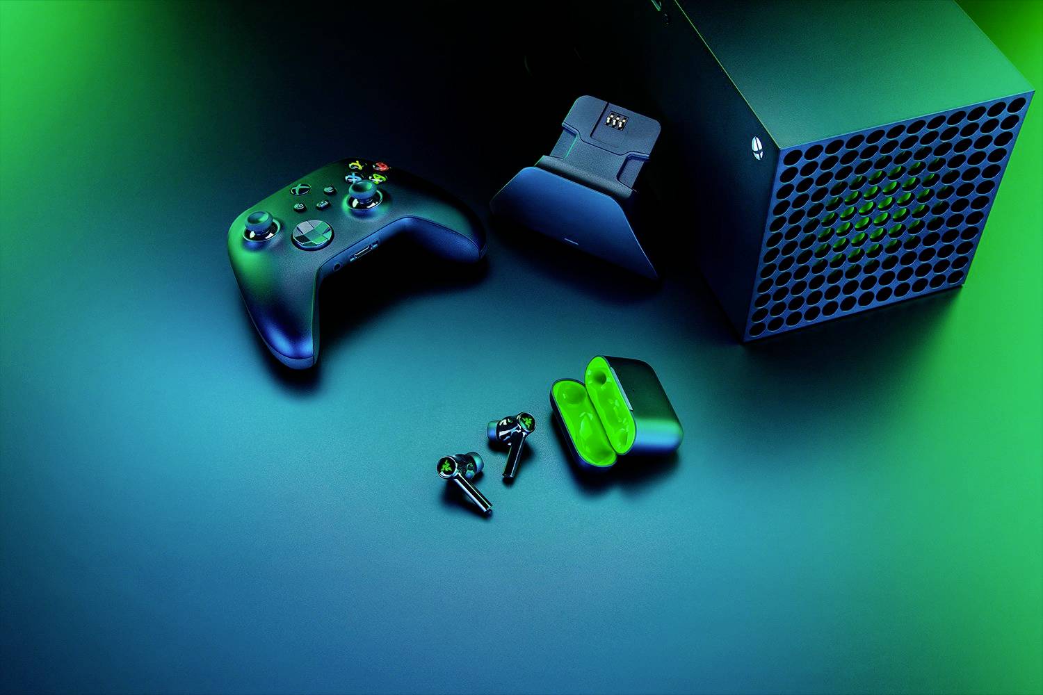 'Controller da gioco e console con stazione di ricarica e auricolari wireless su sfondo illuminato di verde.'