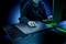 Una persona in una stanza buia usa un computer. La tastiera e il mousepad brillano di luce verde.