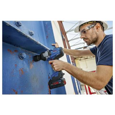 Operaio edile che utilizza un trapano senza fili per fissare una grande trave d'acciaio blu in un cantiere, indossando un casco di sicurezza e occhiali protettivi.