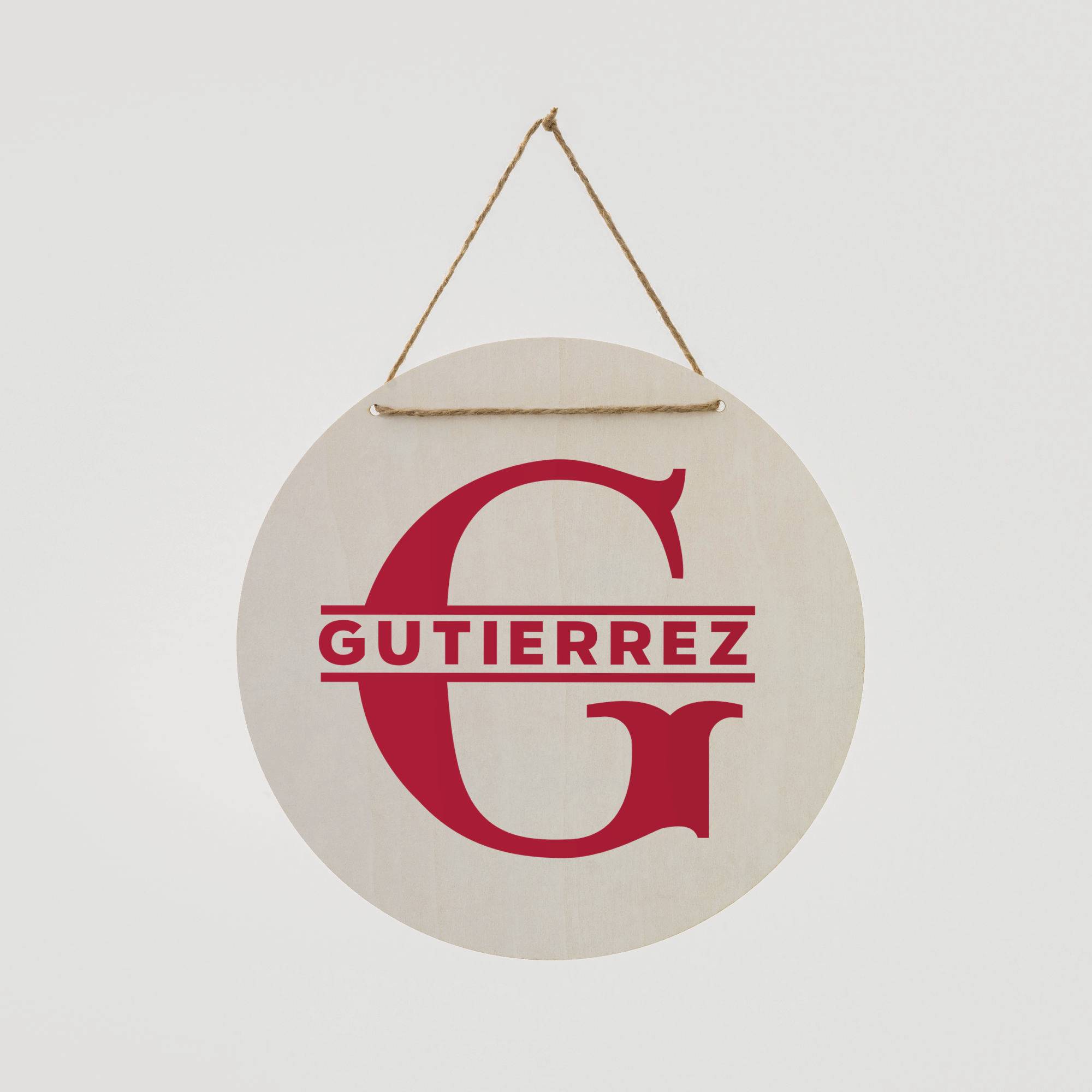 Insegna rotonda in legno con la lettera 'G' rossa e il nome 'Gutierrez' sottostante, appesa a una corda.