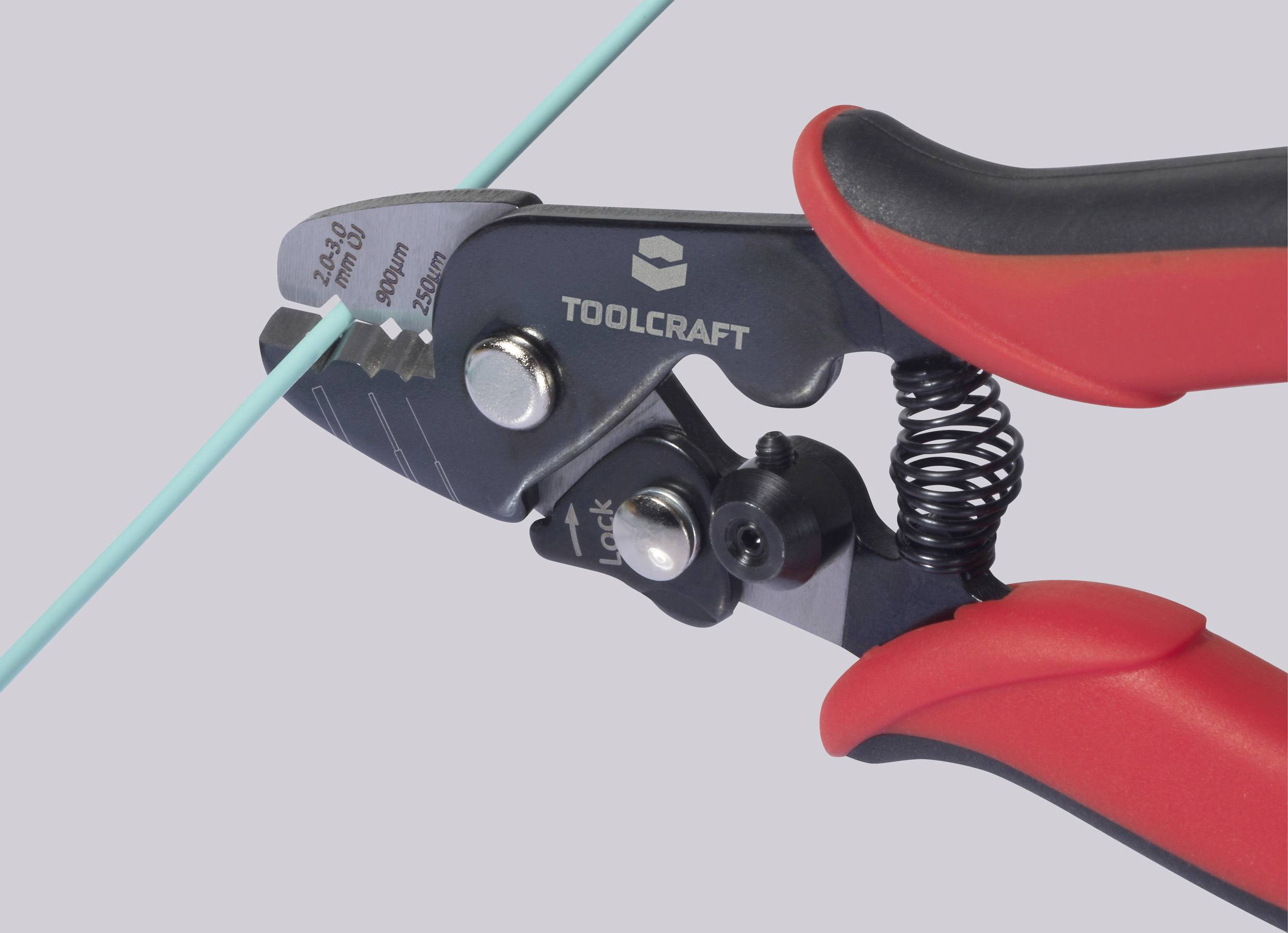 Forbici TOOLCRAFT tagliano un sottile cavo verde. Le impugnature sono rosse e nere, con un meccanismo di blocco.