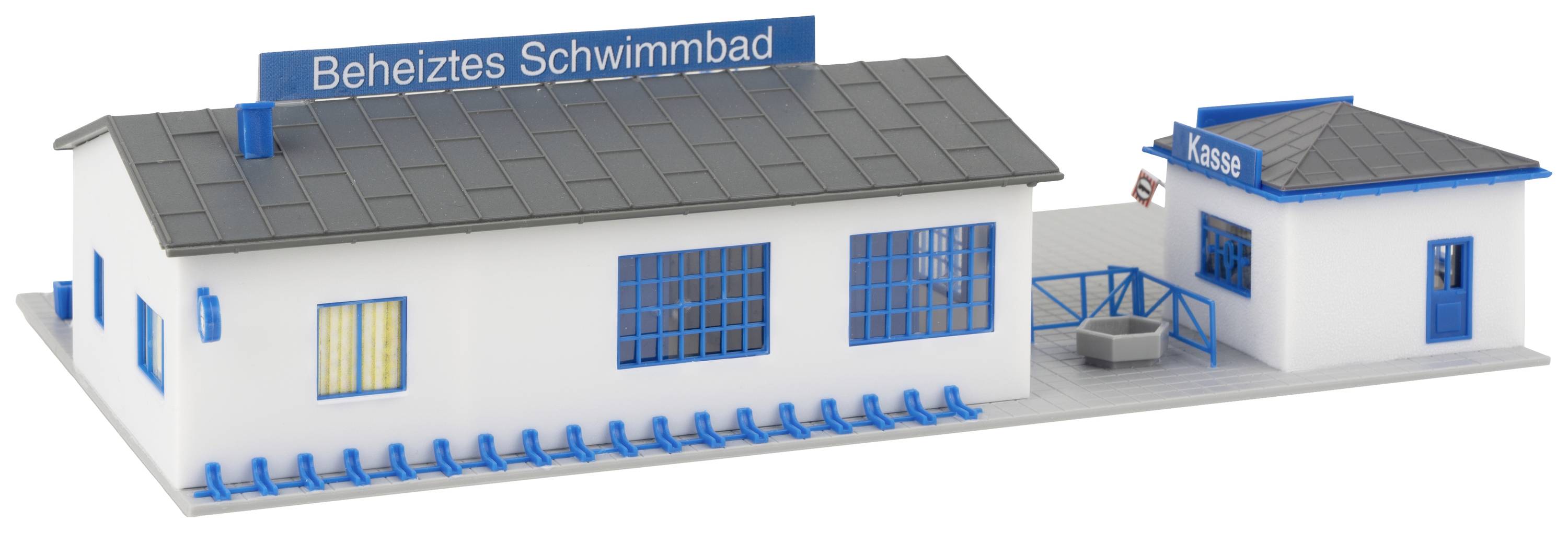 Un modellino in miniatura di una piscina riscaldata con edificio principale, insegna blu e piccola biglietteria.