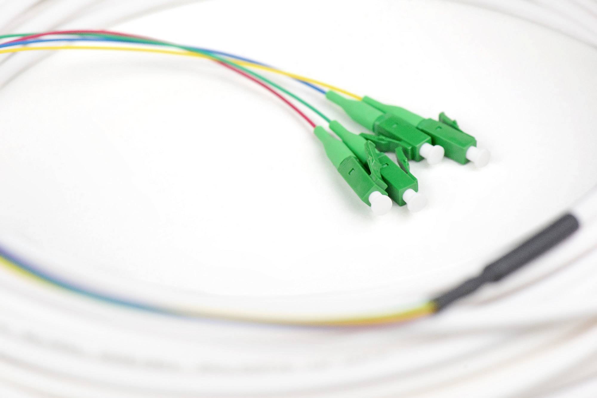 Tre spinotti in fibra ottica verde con cavi colorati su uno sfondo bianco.