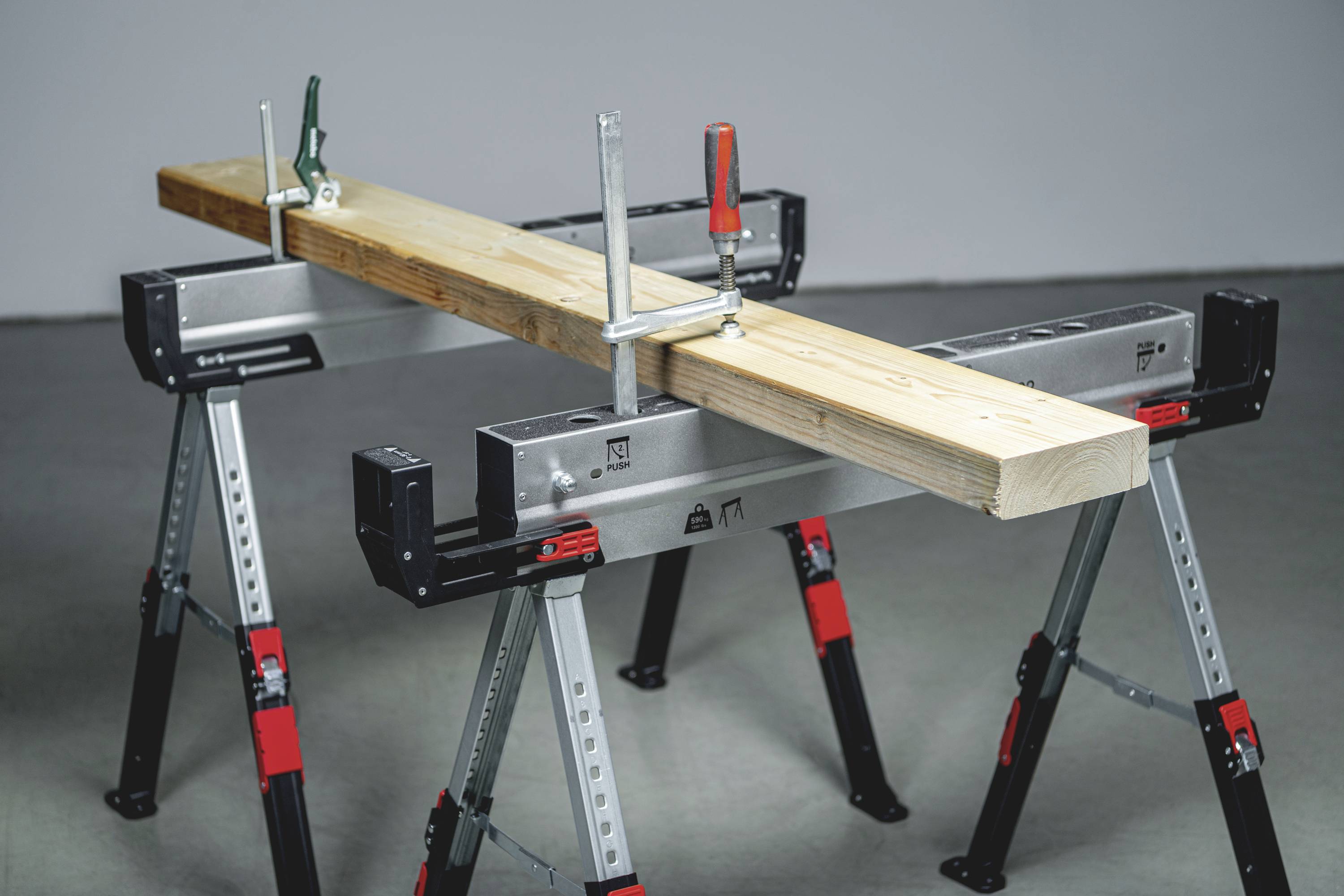 Tavola di legno su due cavalletti metallici, fissata con morsetti.