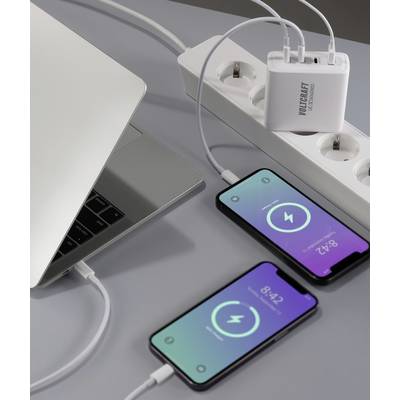 Un laptop e due smartphone sono collegati a una multipresa tramite un caricabatterie. Gli smartphone mostrano simboli di ricarica.