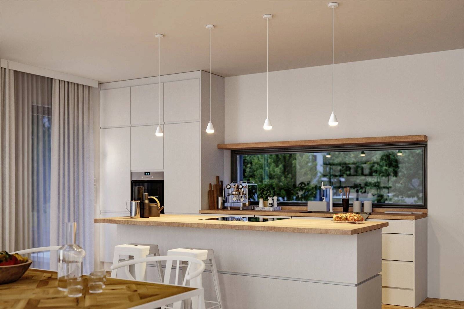 Cucina moderna con elementi in legno, ampia isola centrale, quattro lampade a sospensione, armadi bianchi, forno da incasso e finestra con vista giardino.