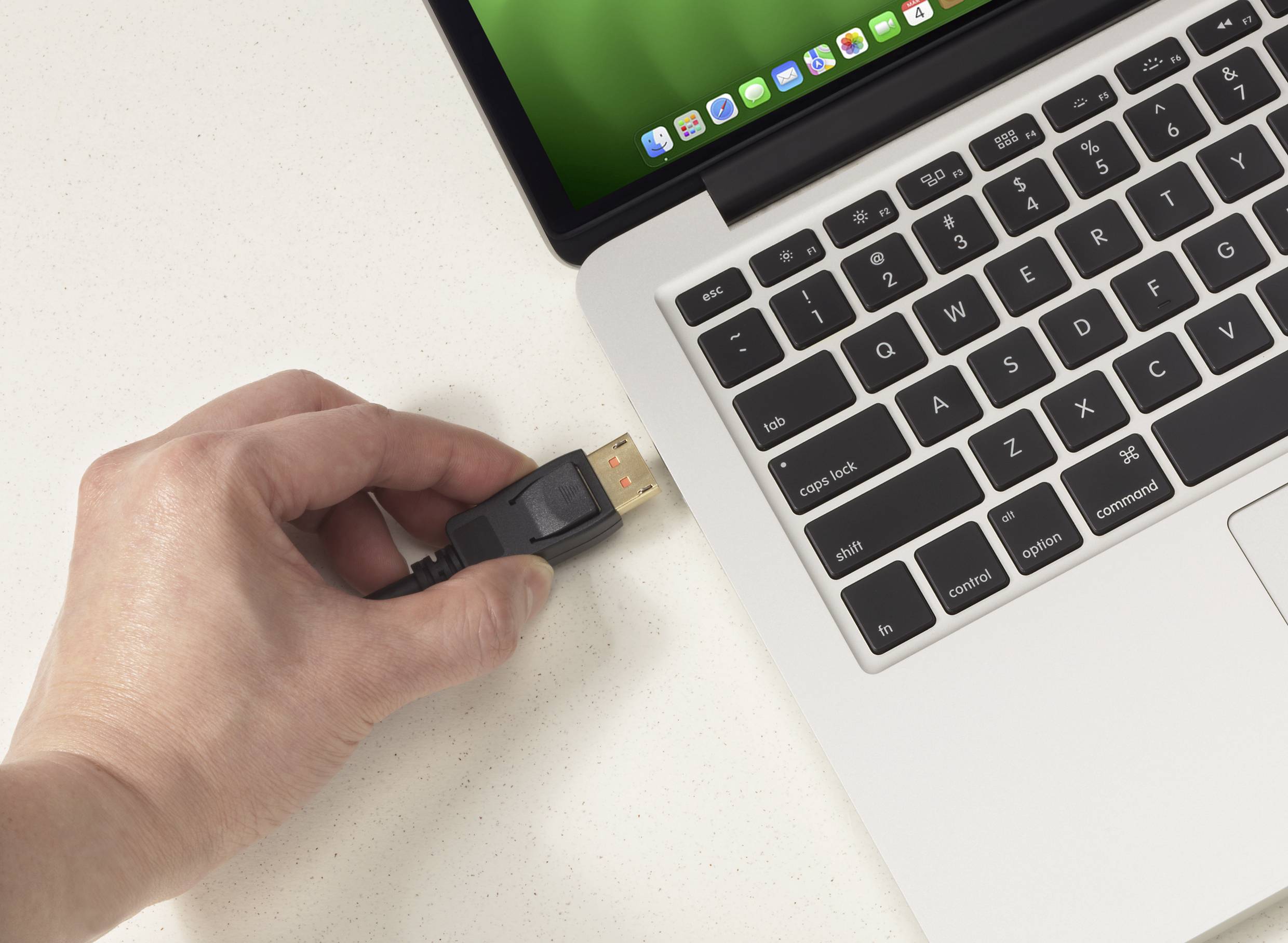 Una persona inserisce un cavo USB nella porta USB di un laptop con la schermata delle app aperta.