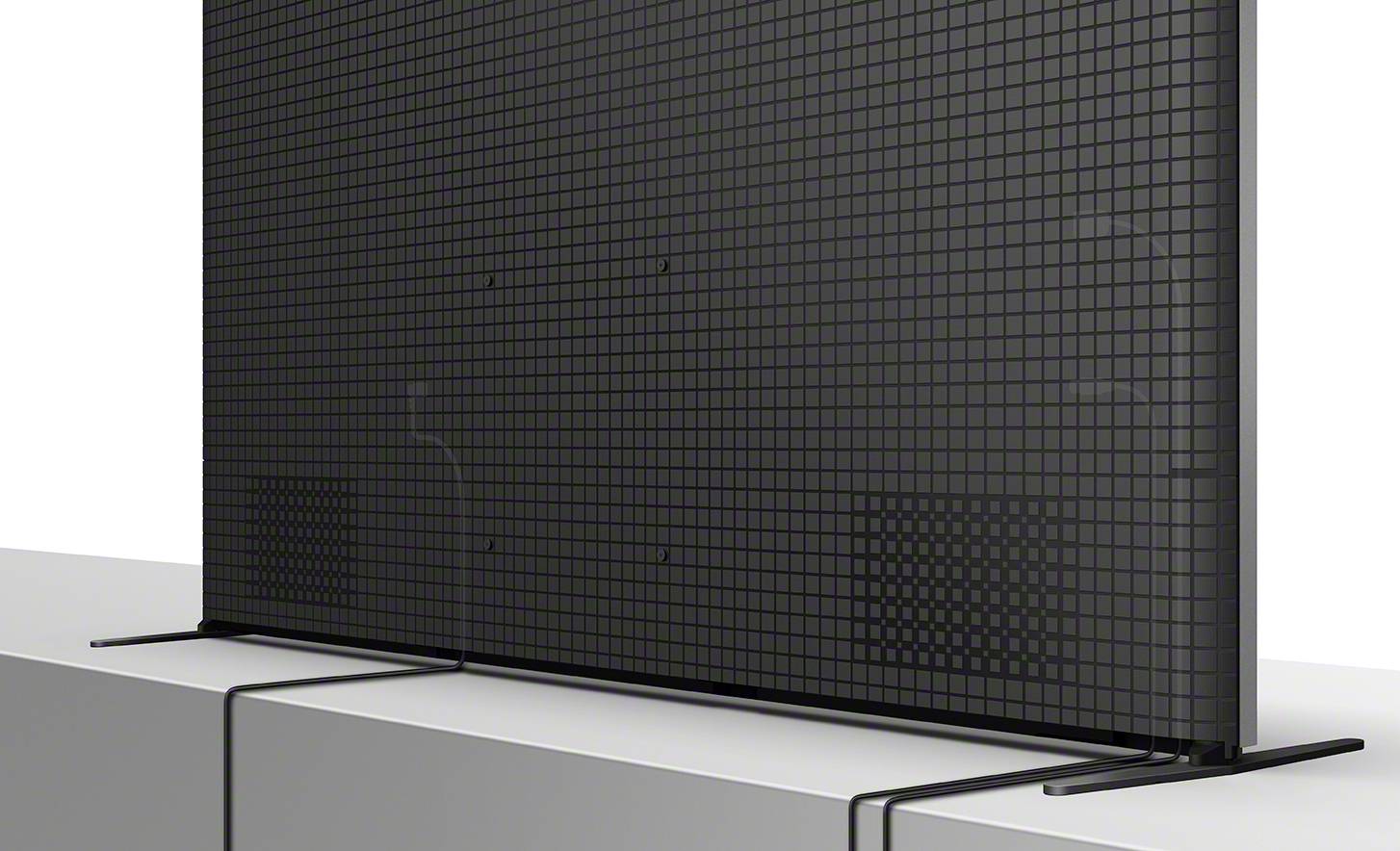 Retro di un televisore moderno con superficie a griglia, base sottile e due altoparlanti integrati.