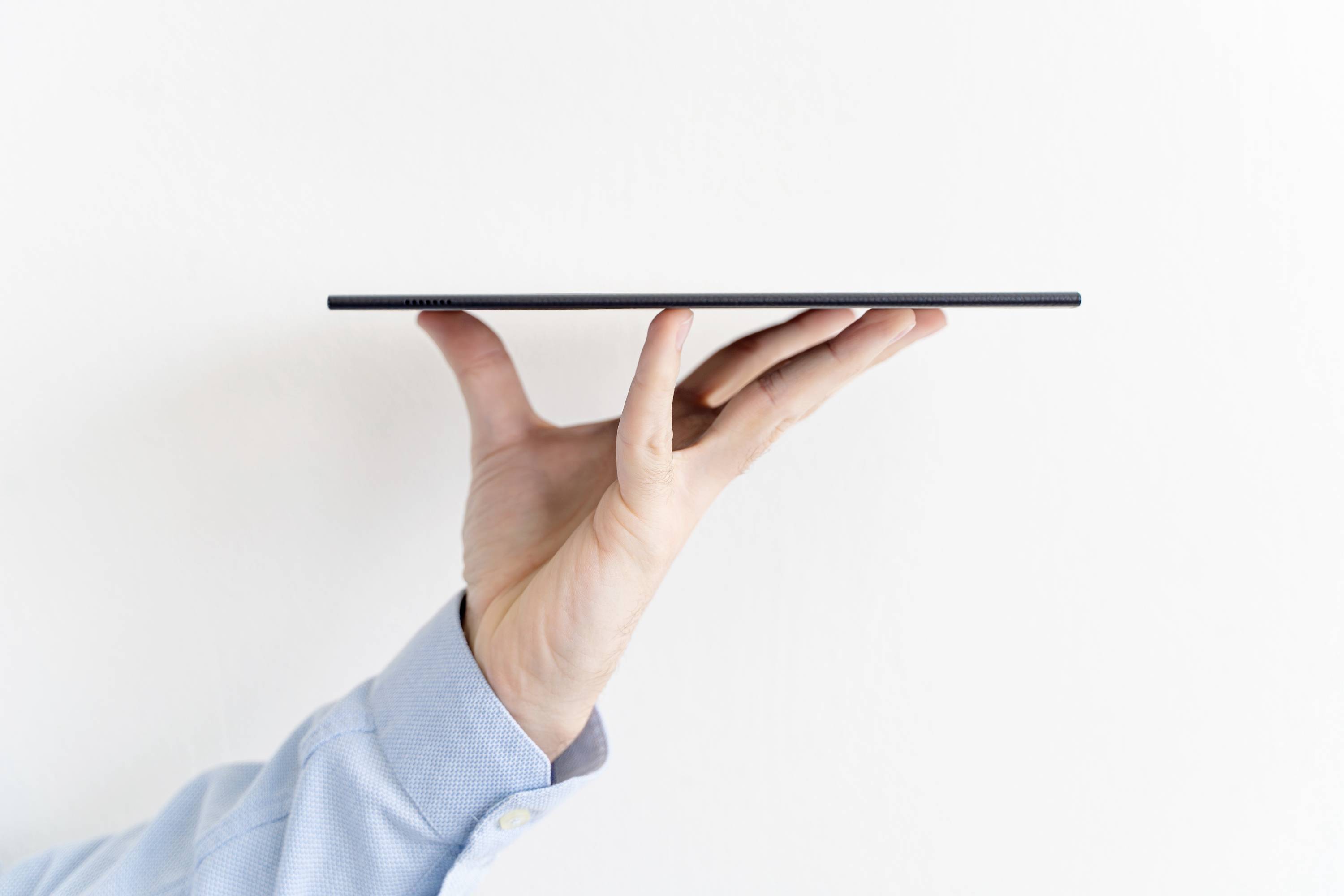 Un tablet viene bilanciato su un palmo di mano, mostrando il suo profilo sottile. Lo sfondo è bianco.