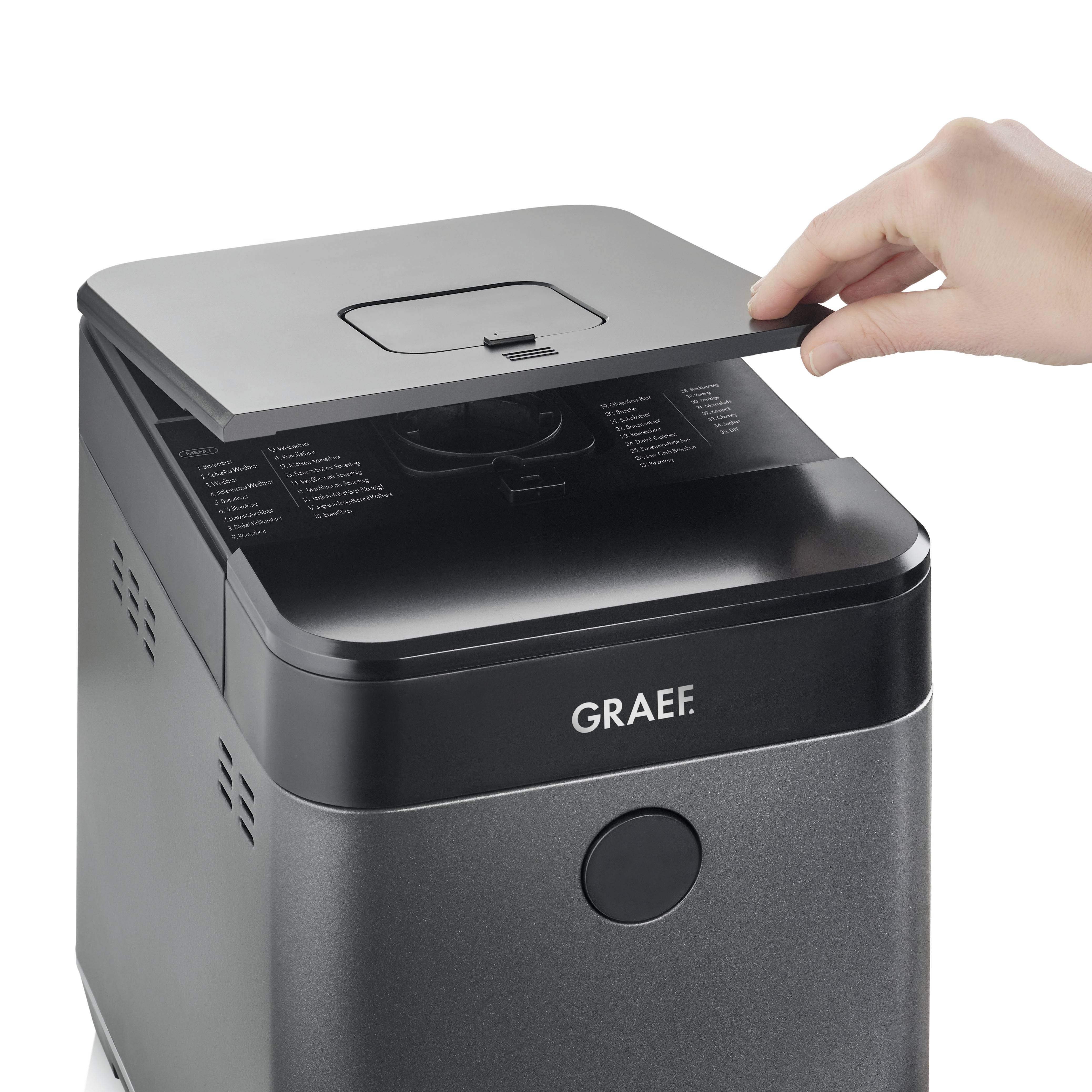 Un macchina per il pane, il cui coperchio viene aperto da una mano.