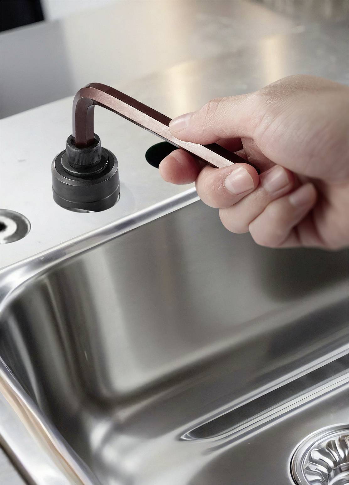 Una mano apre un rubinetto sopra un lavandino in acciaio inox.
