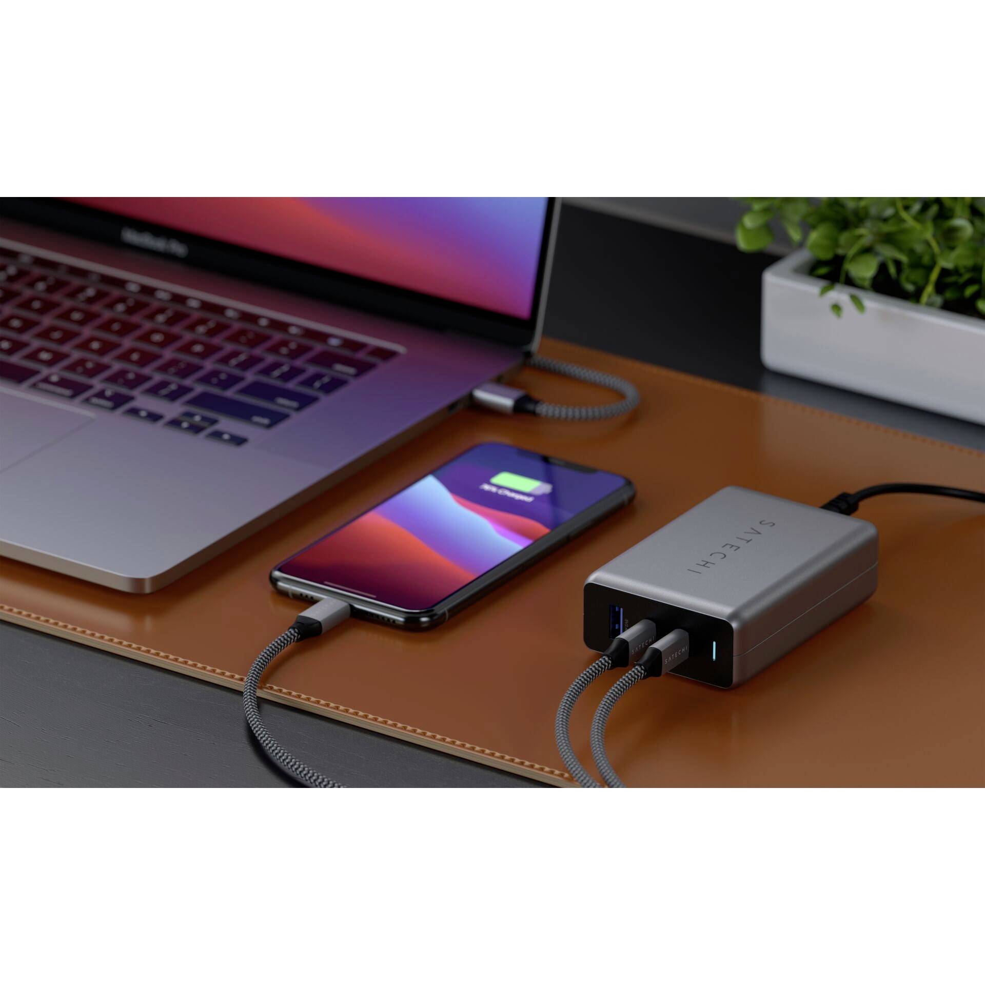 Laptop e smartphone su un tavolo, entrambi in carica tramite un caricabatterie.