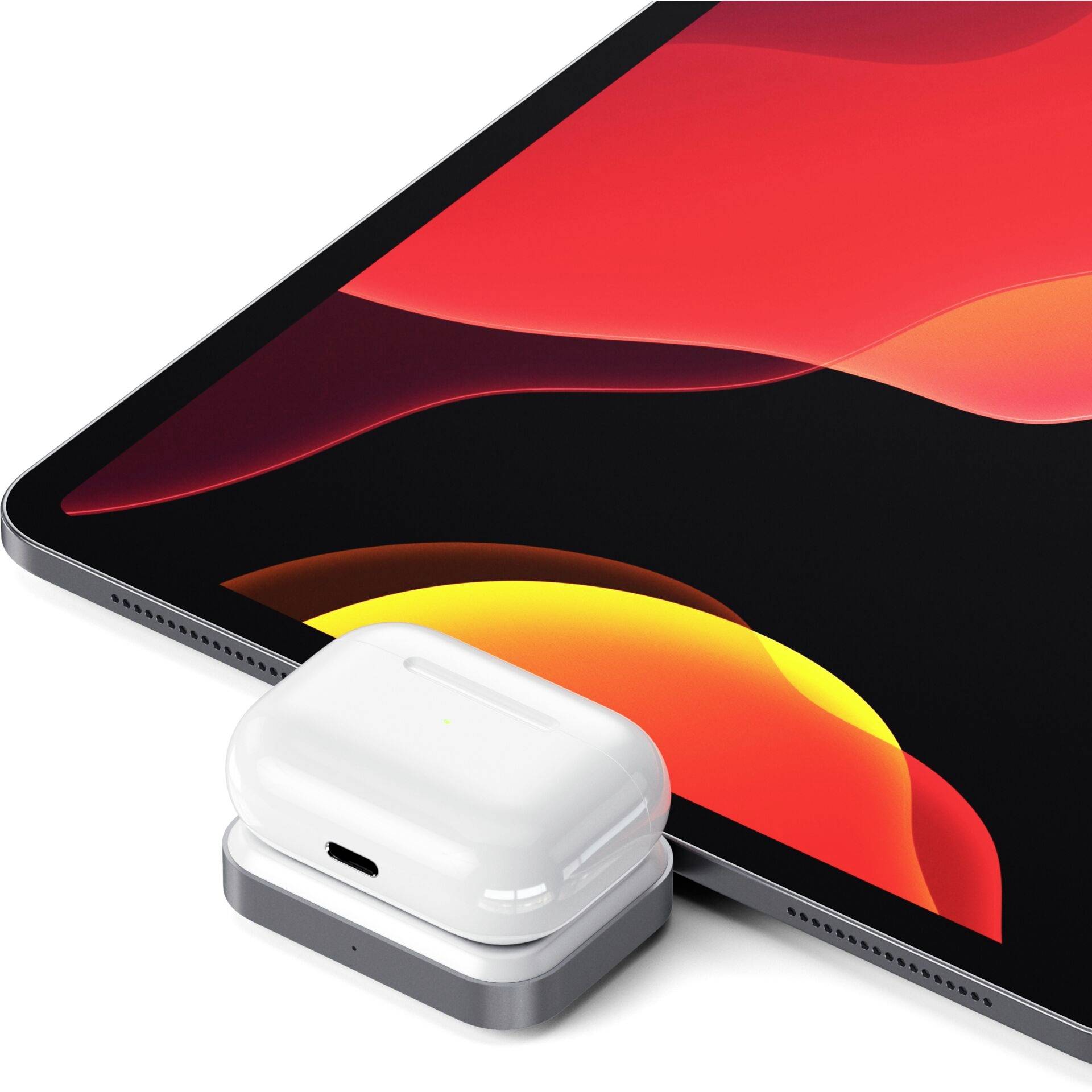 Un tablet con uno schermo colorato accanto a un custodia per auricolari wireless posizionata su un caricabatterie.