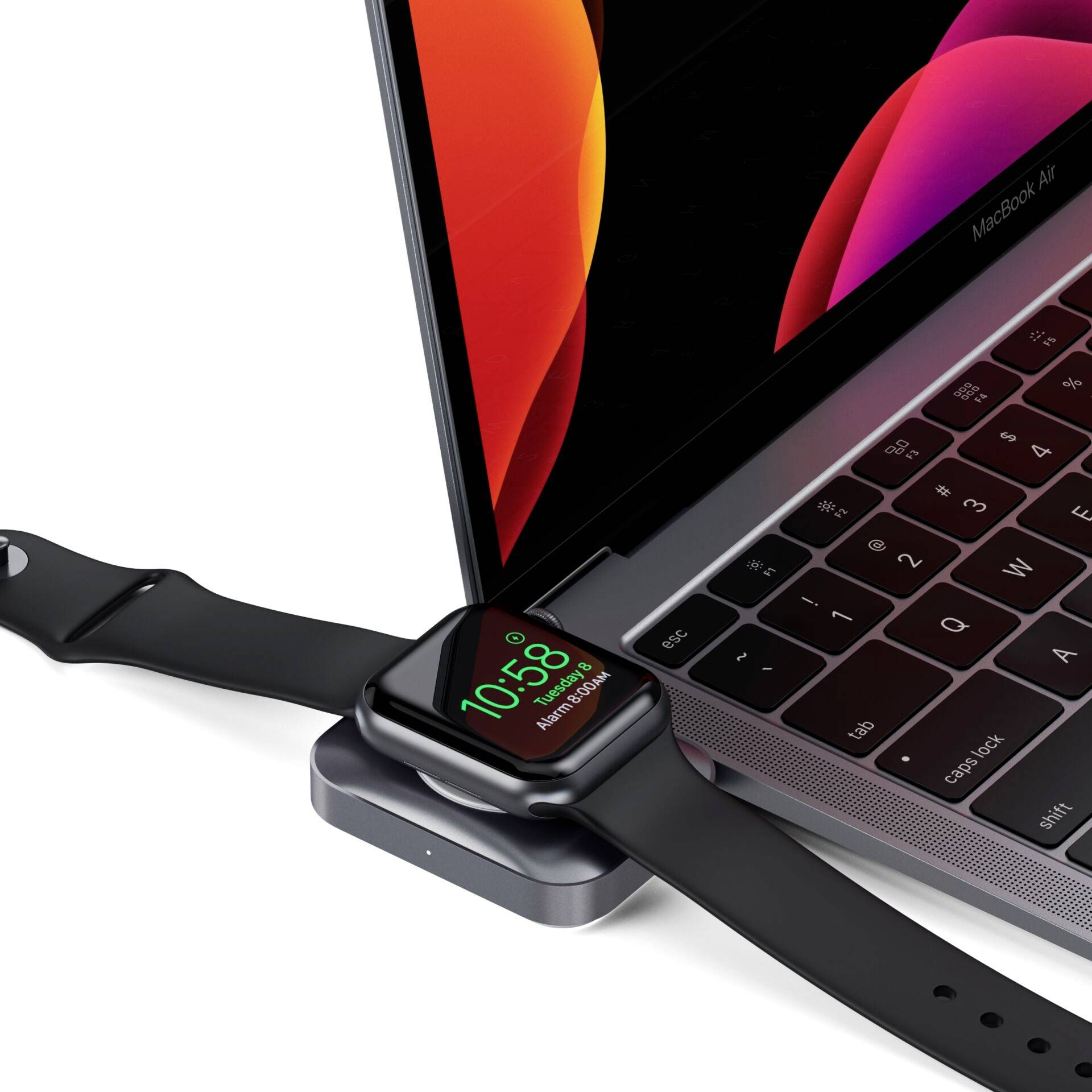 Un smartwatch viene caricato su un laptop. L'orologio mostra l'ora 10:58. Lo schermo del laptop mostra forme luminose di colore arancione.