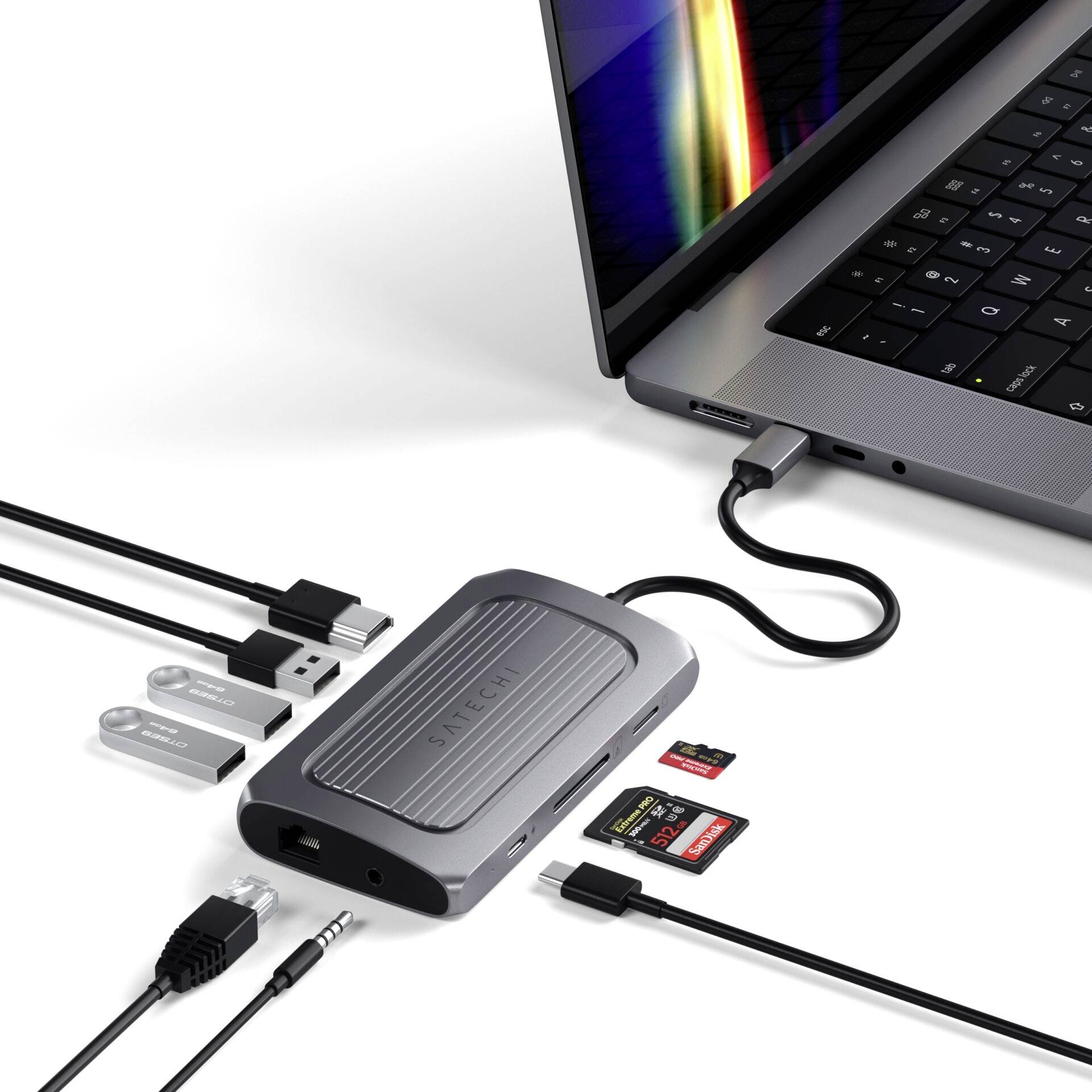 MacBook con hub USB-C collegato, vari cavi e schede di memoria. L'hub estende le possibilità di connessione del laptop.