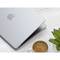 Laptop parzialmente aperto con custodia argentata, accanto a una tazza di caffè e una pianta su un tavolo chiaro.