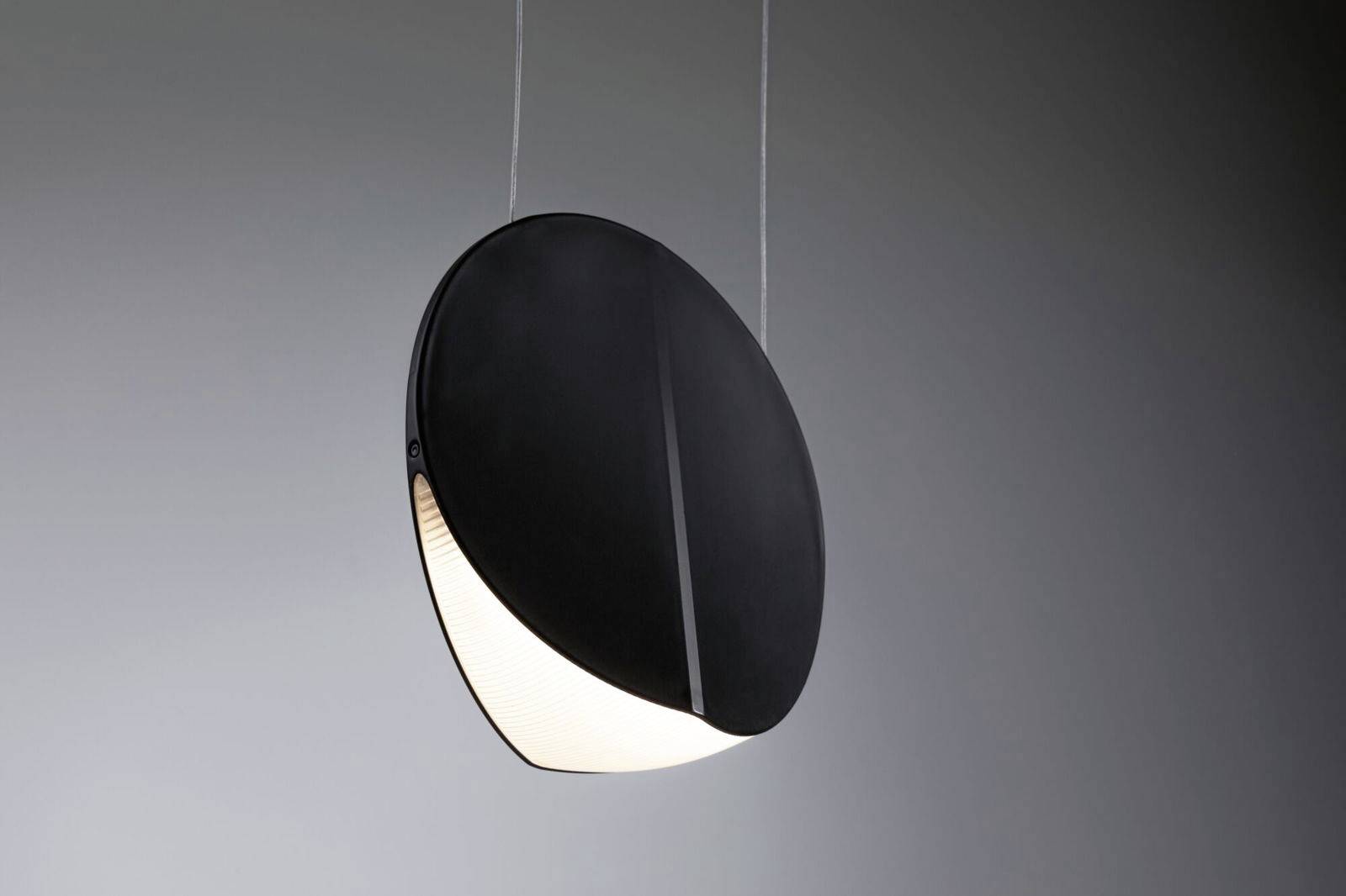 Una lampada a sospensione moderna e rotonda con un involucro nero e un'area luminosa a semicerchio nella metà inferiore.