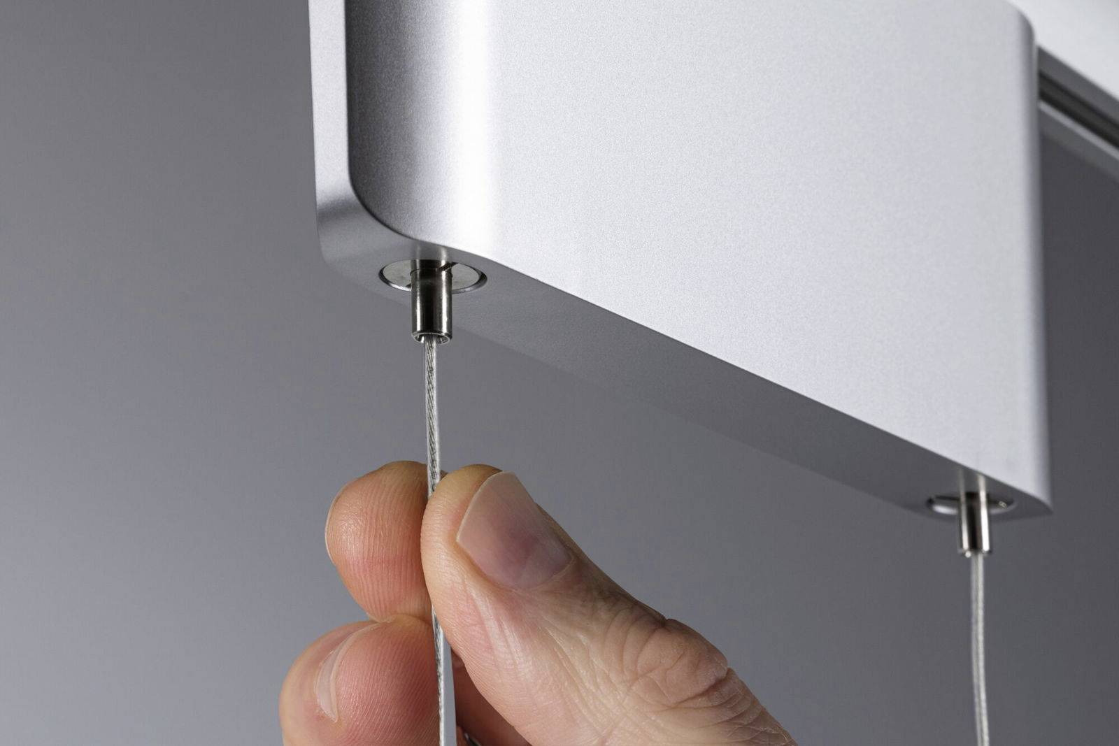 Una mano tira delicatamente un sottile cavo che viene inserito in un dispositivo metallico moderno.