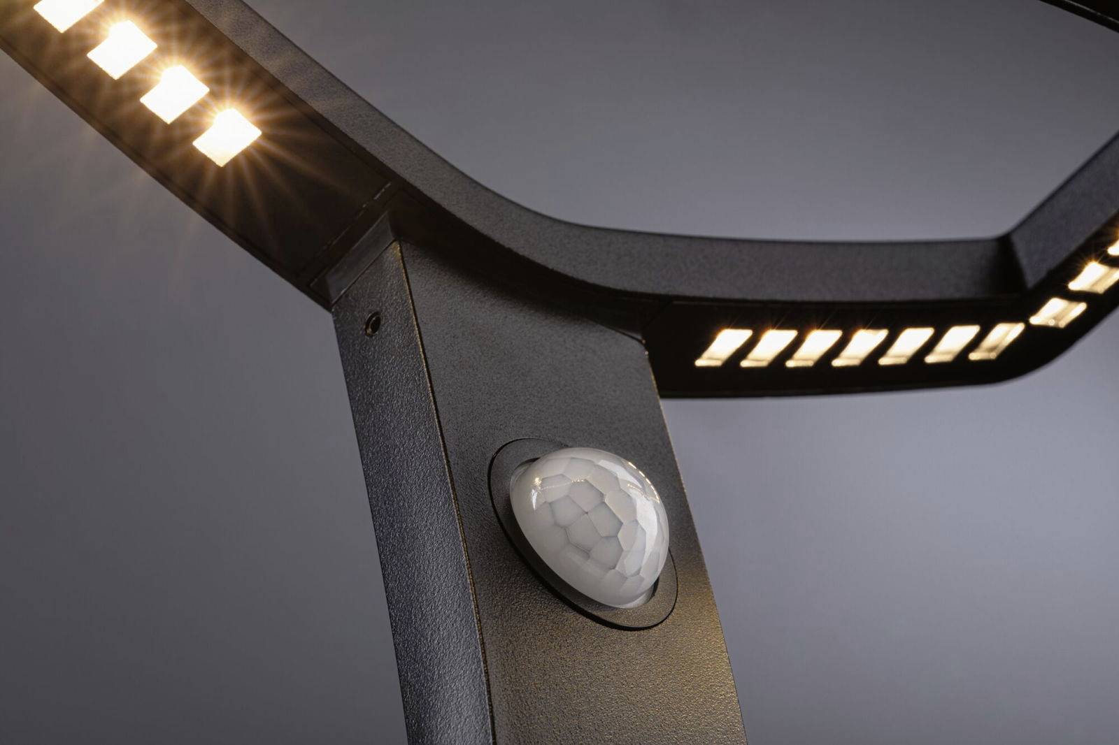 Primo piano di un moderno lampione a LED con sensore di movimento integrato, che emana una luce calda e uniforme.