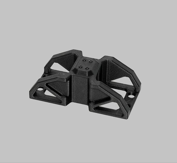 Un componente rettangolare nero in plastica con quattro gambe inclinate, collegate da un'elevazione centrale.