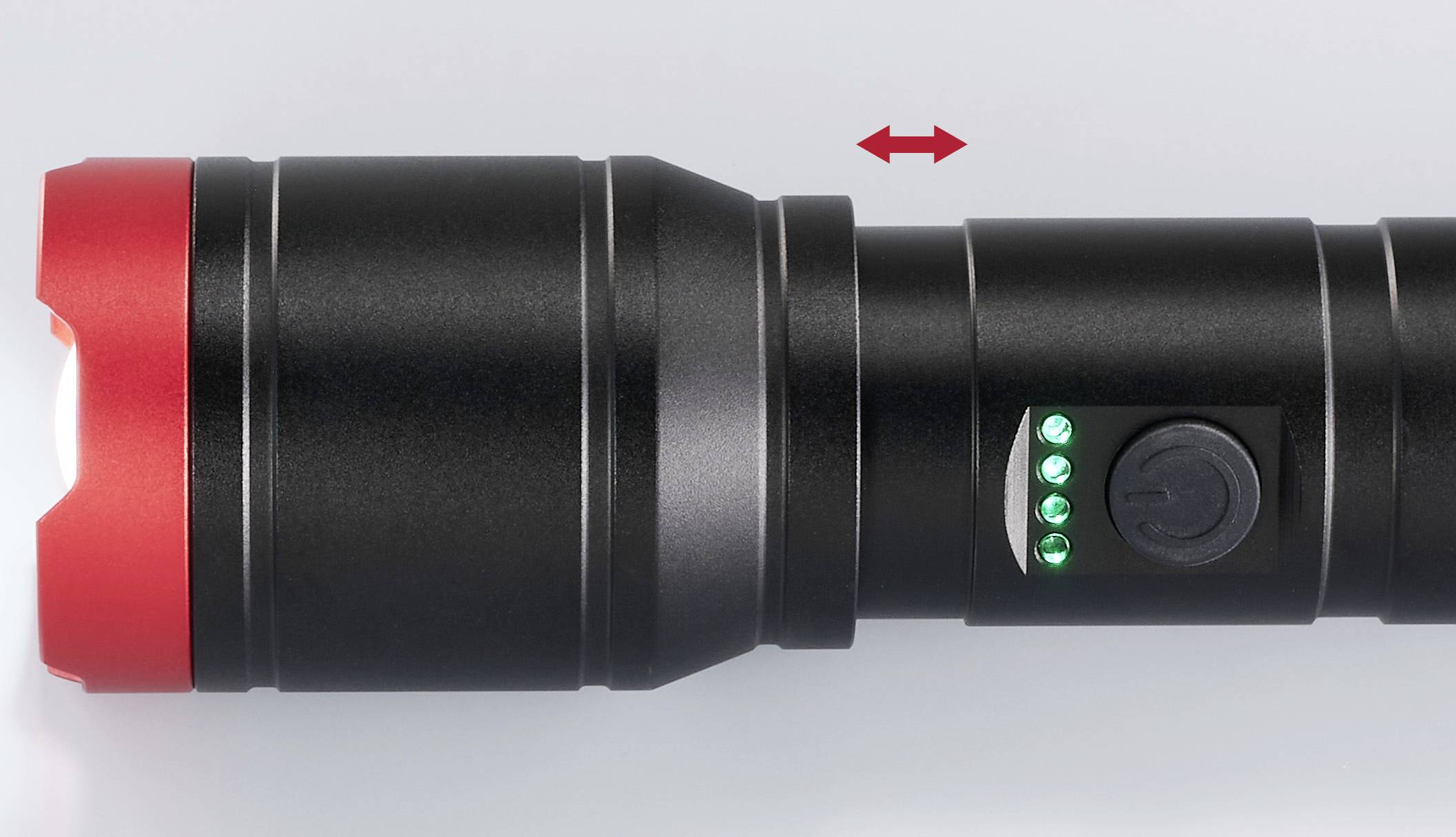 Torcia nera con bordo rosso, tre indicatori LED verdi illuminati e un interruttore di accensione/spegnimento. Una freccia indica la funzione estensibile.