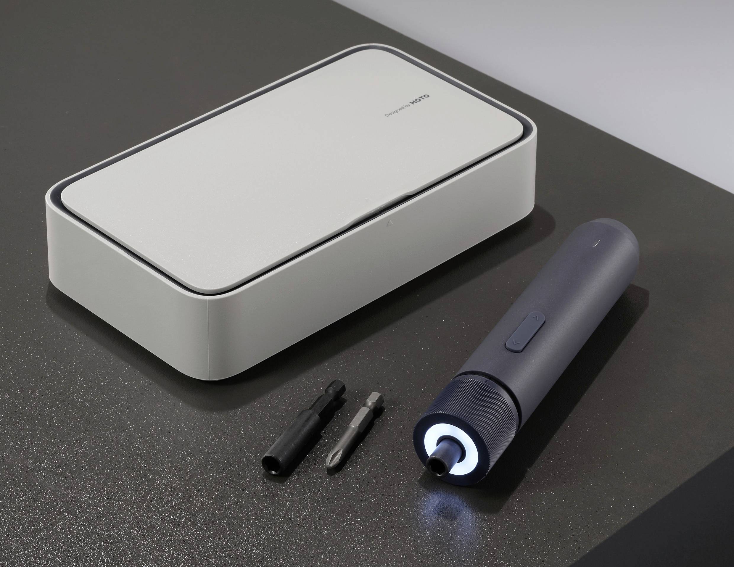 Cacciavite elettrico blu scuro con due punte davanti a una scatola grigia. In evidenza: luce LED sul cacciavite.