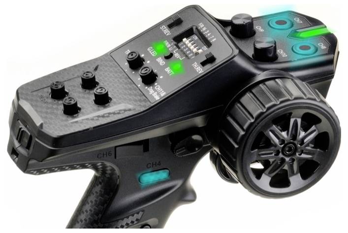 Telecomando con pulsanti di controllo, manopole rotanti e interruttori. Illuminato in verde in alcuni punti. Utilizzato per il controllo di auto radiocomandate.