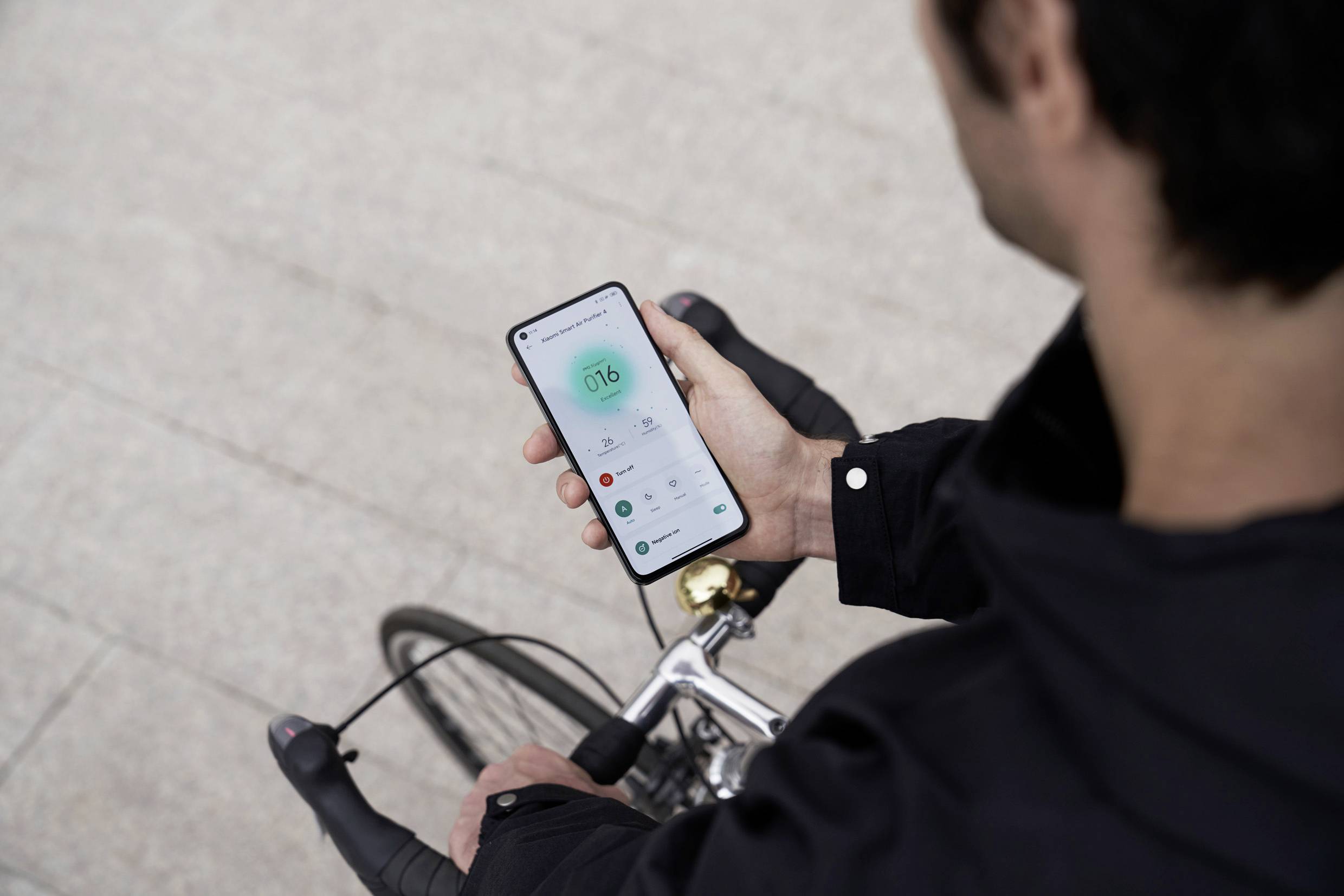 Una persona tiene uno smartphone in mano mentre è seduta su una bicicletta. Sul display è visibile un'app per il fitness.