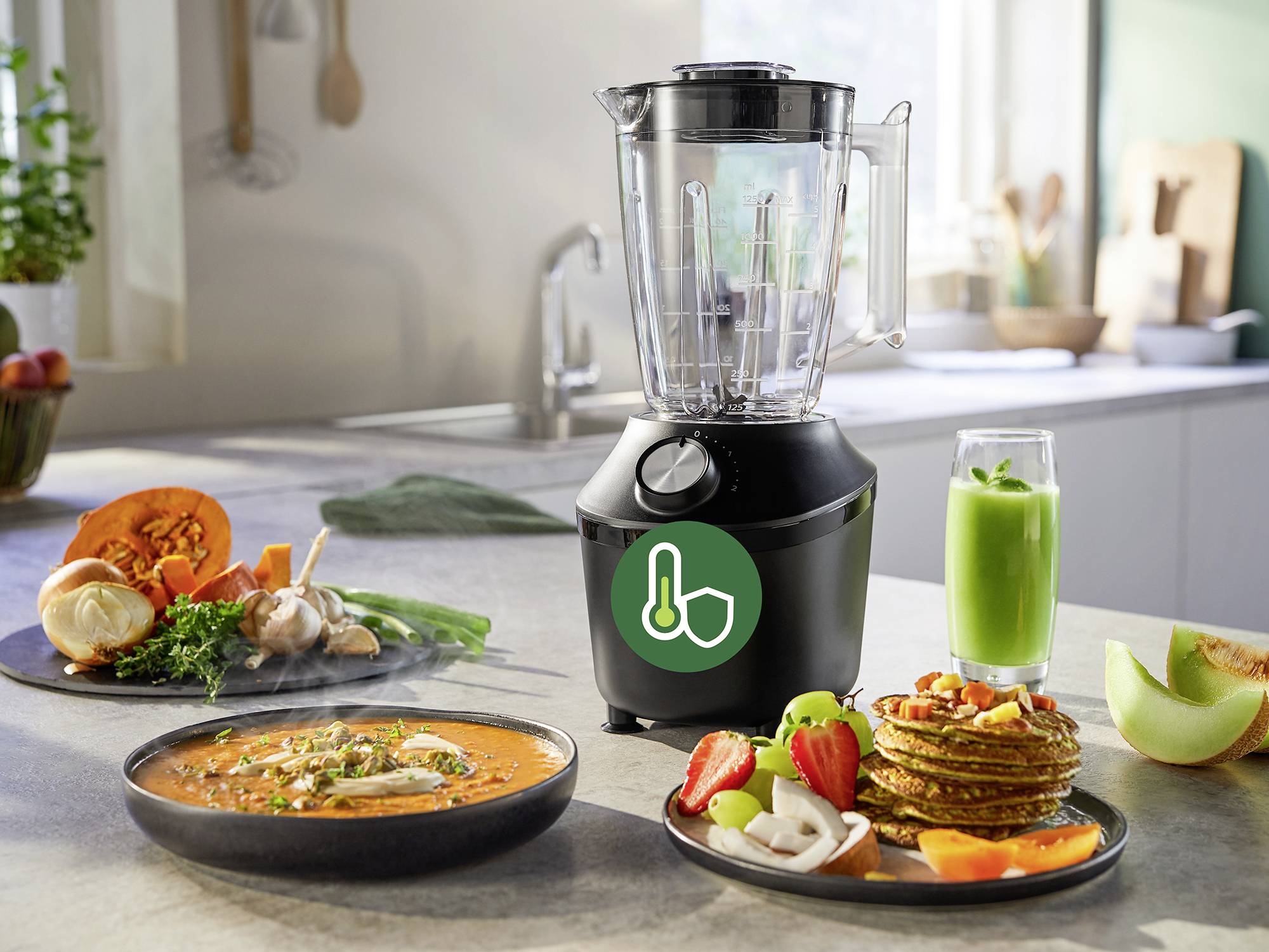 'Un frullatore su un piano da cucina, circondato da ingredienti freschi, verdure, zuppa, pancake con frutta e un bicchiere di succo verde.'