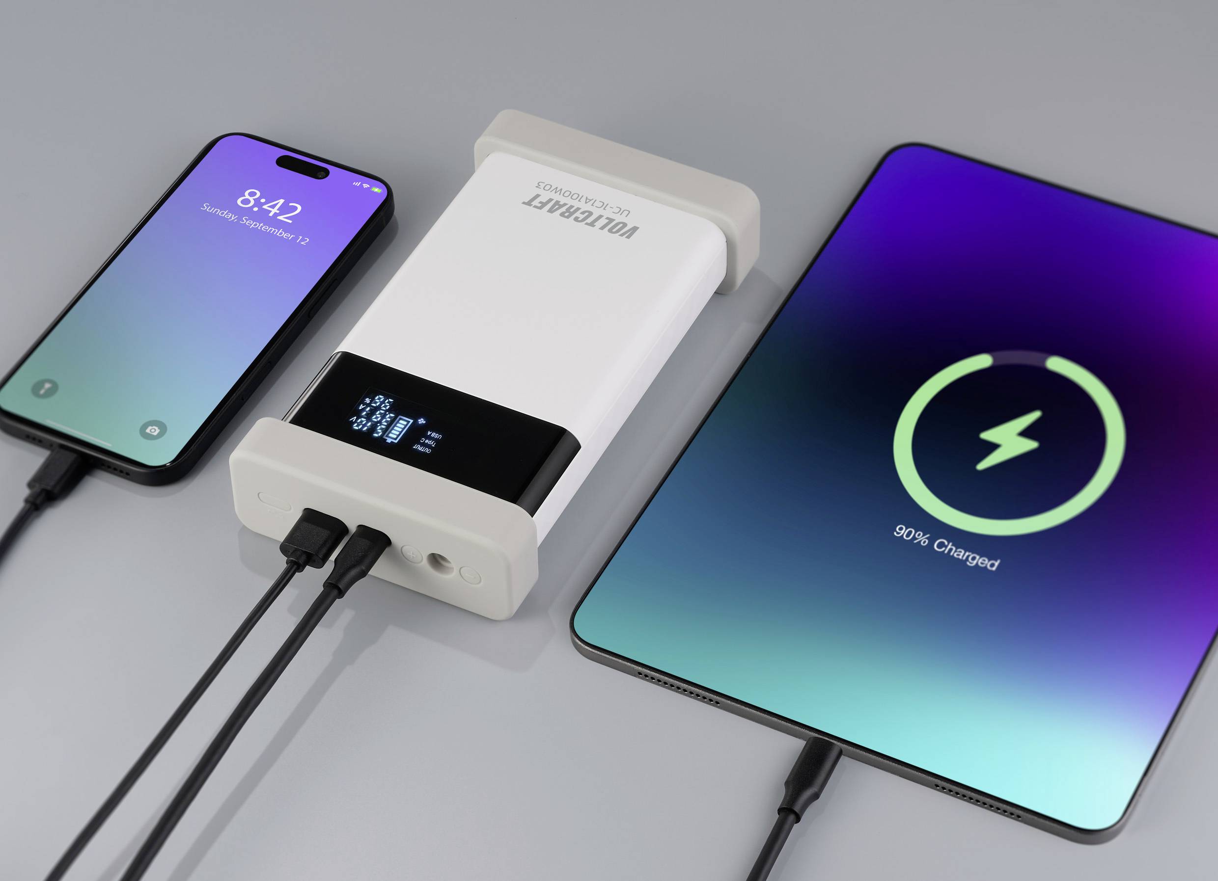Un smartphone e un tablet vengono caricati con un caricabatterie portatile. Lo smartphone mostra l'ora '8:42', il tablet è carico al 90%.