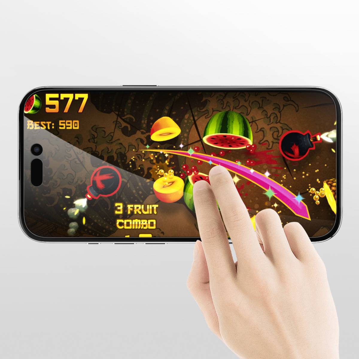 Una mano sta giocando a un gioco mobile in cui la frutta viene tagliata con movimenti di swipe. Il punteggio mostra 577 con un miglior risultato di 590.