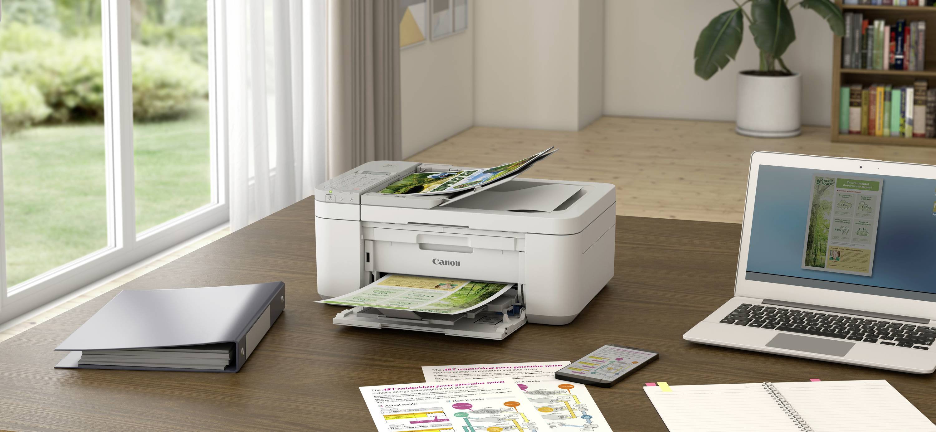 Una stampante su un tavolo di legno accanto a un laptop e a una cartella in una stanza ben illuminata. La stampante sta stampando un documento.