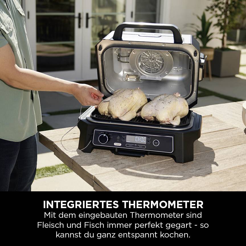 Una persona controlla due polli in un barbecue aperto con un termometro integrato. Testo: Termometro integrato.