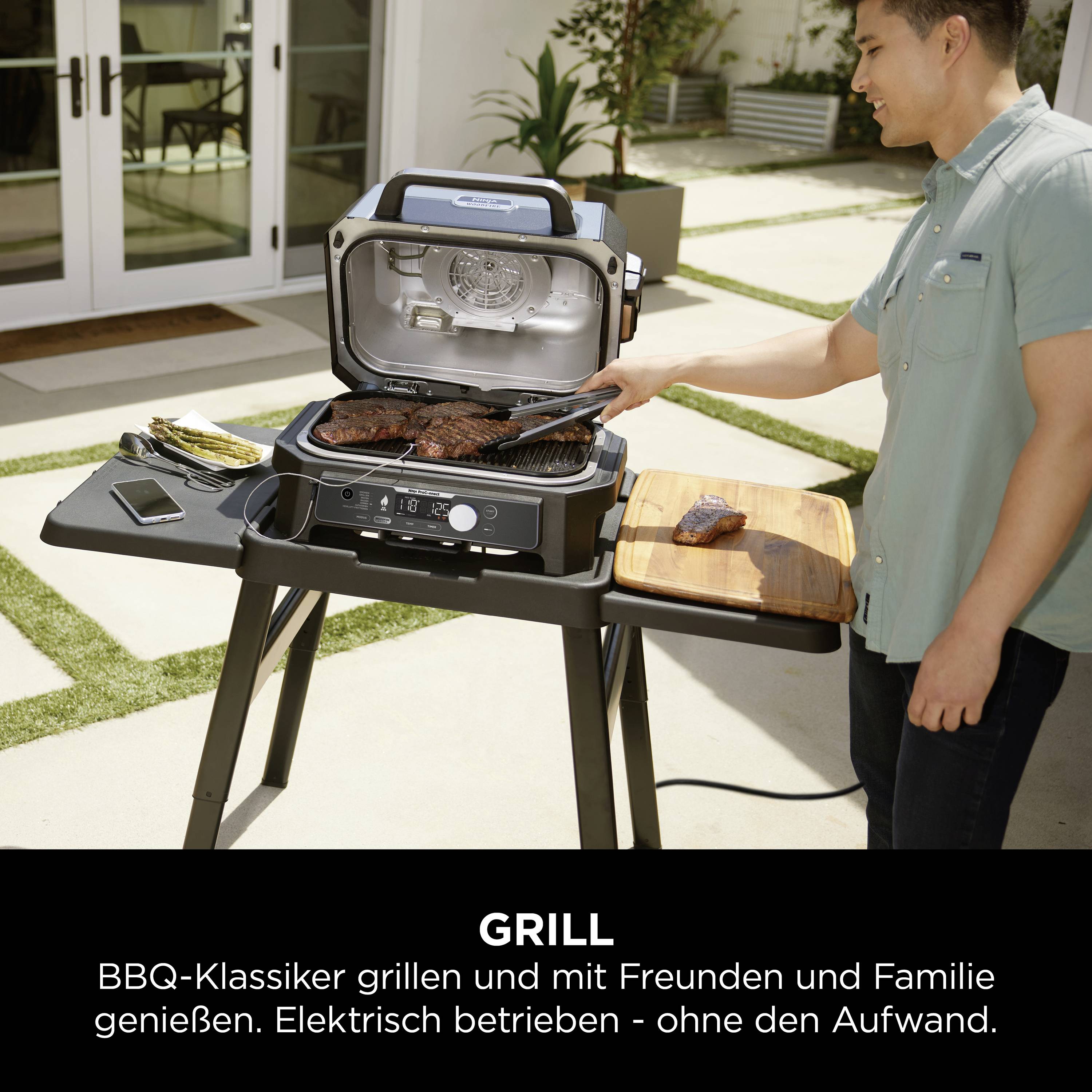 Una persona è in piedi accanto a un barbecue elettrico in giardino. Cibo da grigliare è posto sulla griglia e su un tagliere nelle vicinanze. Testo: 'Grigliare i classici del BBQ e godersi momenti con amici e famiglia'.