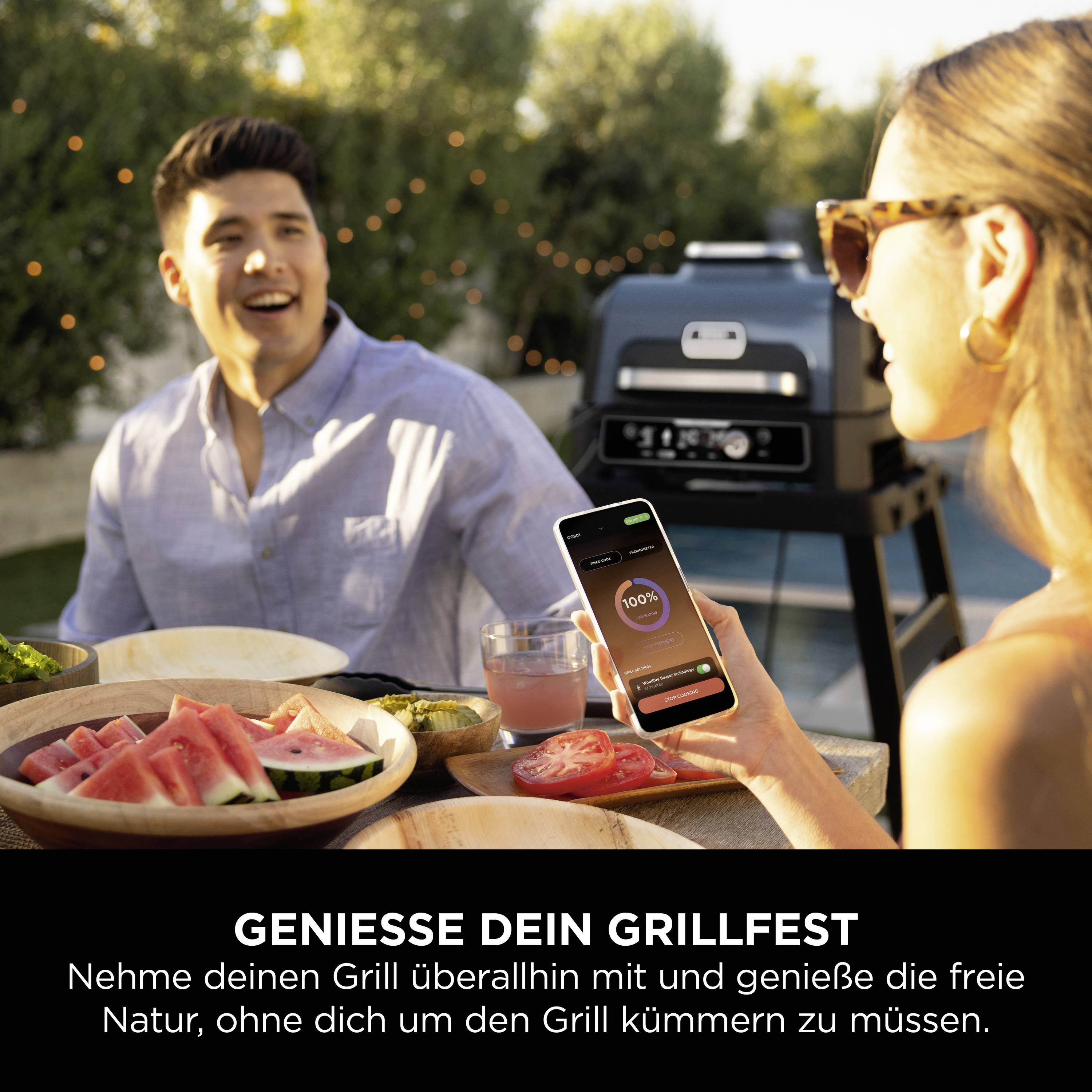 Una donna mostra a un uomo uno smartphone con un'app per grigliare. Sullo sfondo un barbecue. Testo: 'Goditi la tua festa alla griglia'.