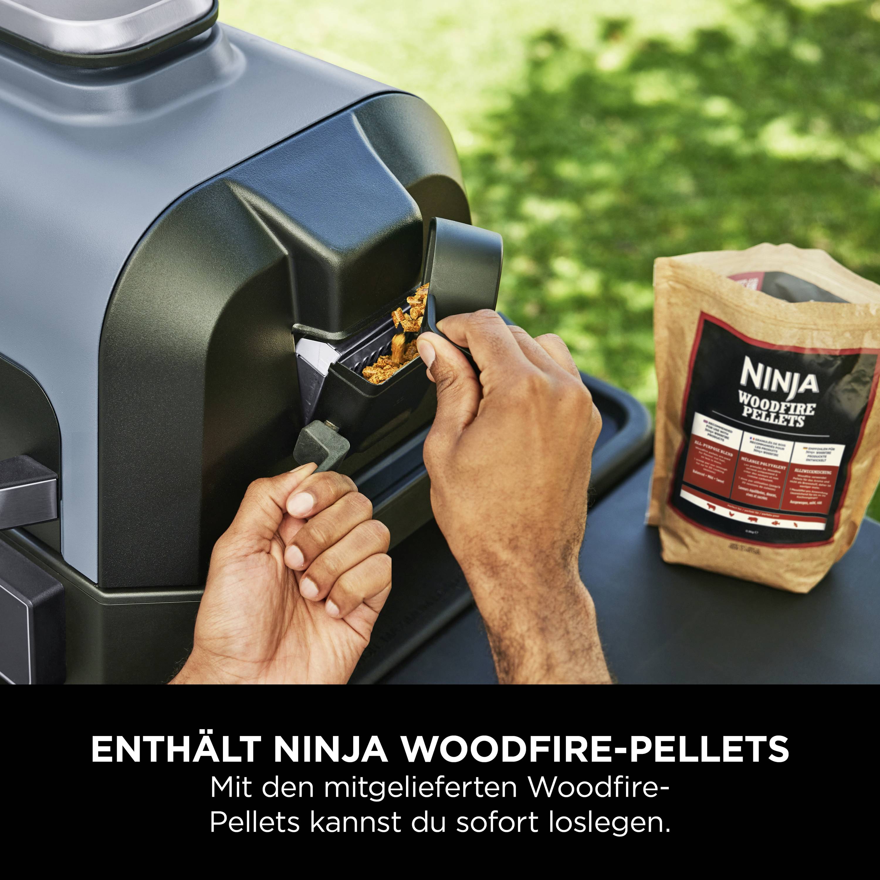 'Mano riempie pellet di legno Ninja Woodfire nel grill. Sacchetto di pellet sul tavolo accanto.'