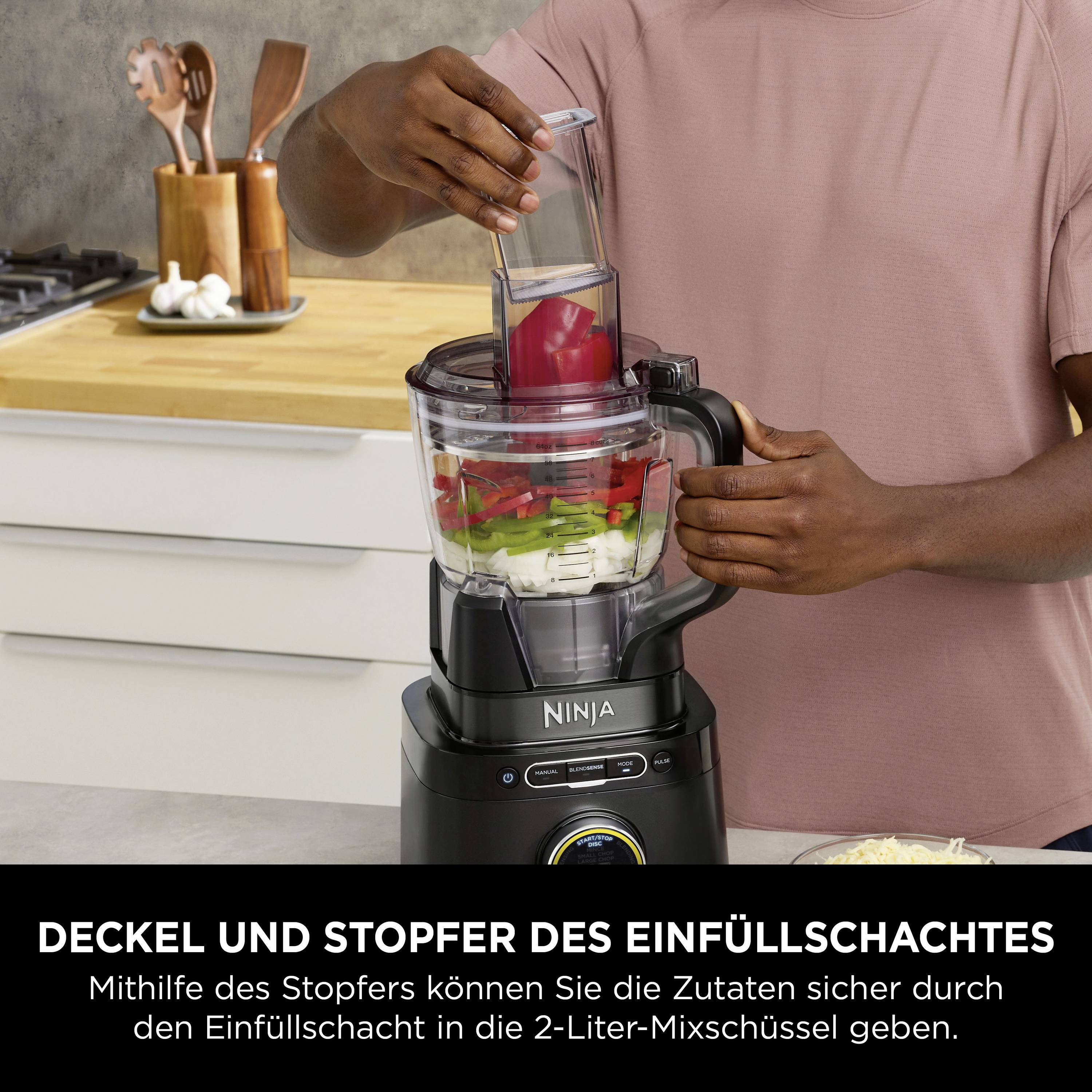 Un uomo sta mettendo ingredienti in un frullatore con l'etichetta 'Coperchio e pestello dell'imboccatura'. Cucina sullo sfondo.
