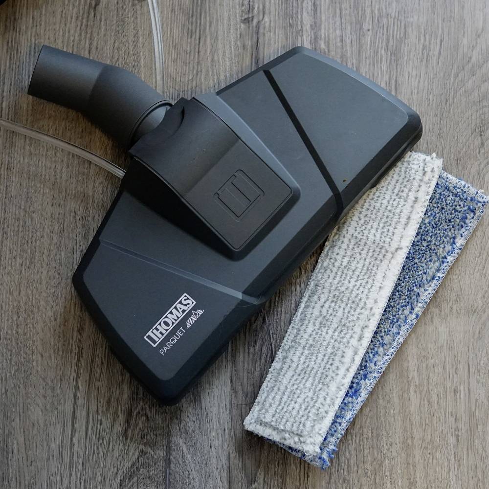 Bocchetta dell'aspirapolvere con pad in microfibra su un pavimento in legno. Prodotto Thomas per la pulizia del parquet.