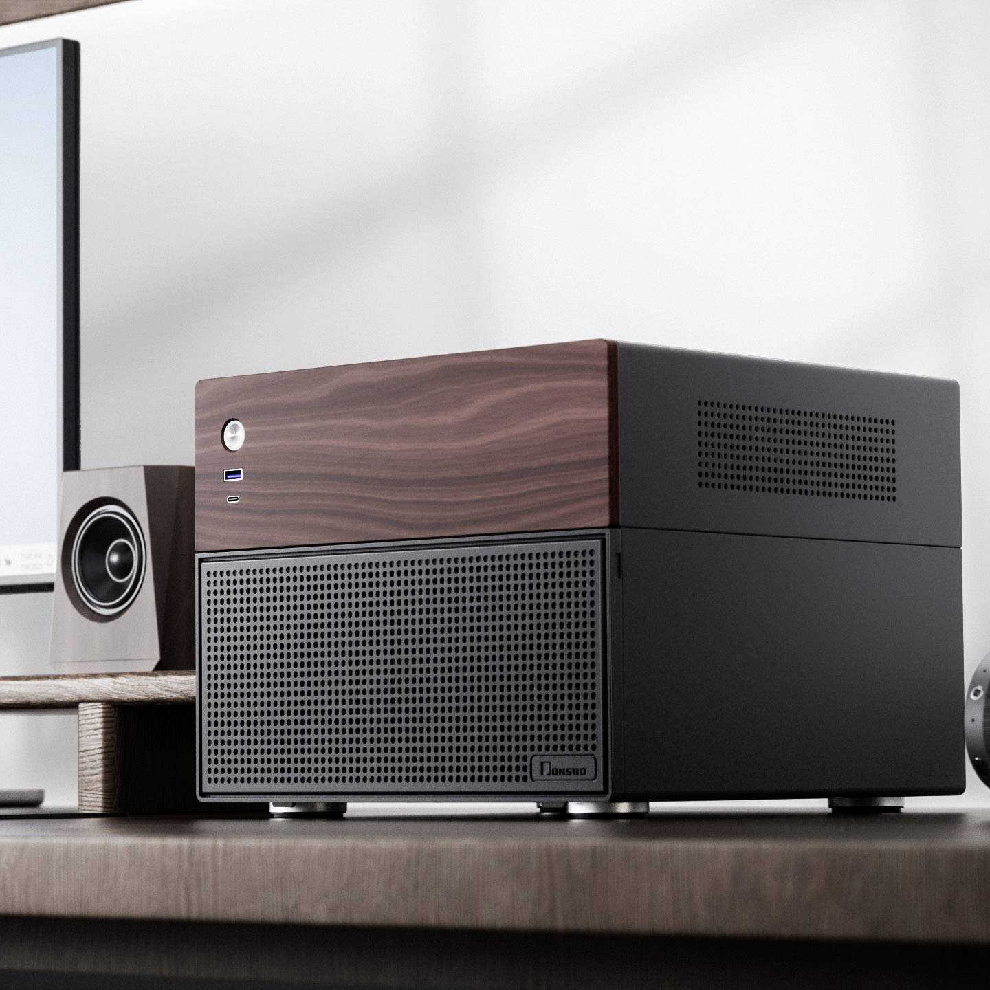 Torre del computer nera con superficie in legno su una scrivania, accanto a un monitor e altoparlanti. Design moderno e minimalista.