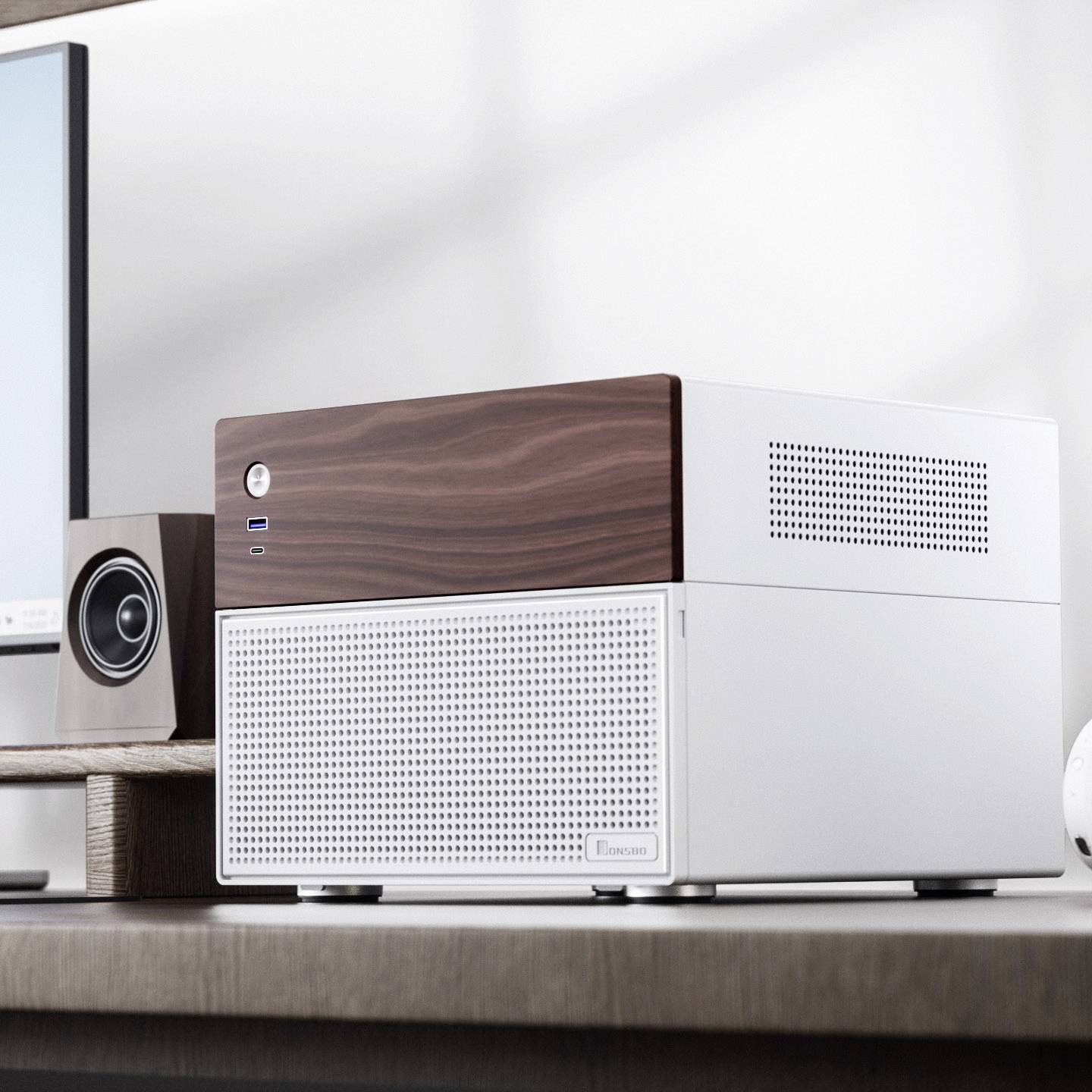 Un case per computer moderno con finitura effetto legno è posizionato su una scrivania accanto a un monitor e un altoparlante.