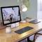 Una scrivania con un monitor che mostra un gatto. Accanto ci sono una lampada da tavolo, una tazza di caffè, un orologio digitale e un laptop.