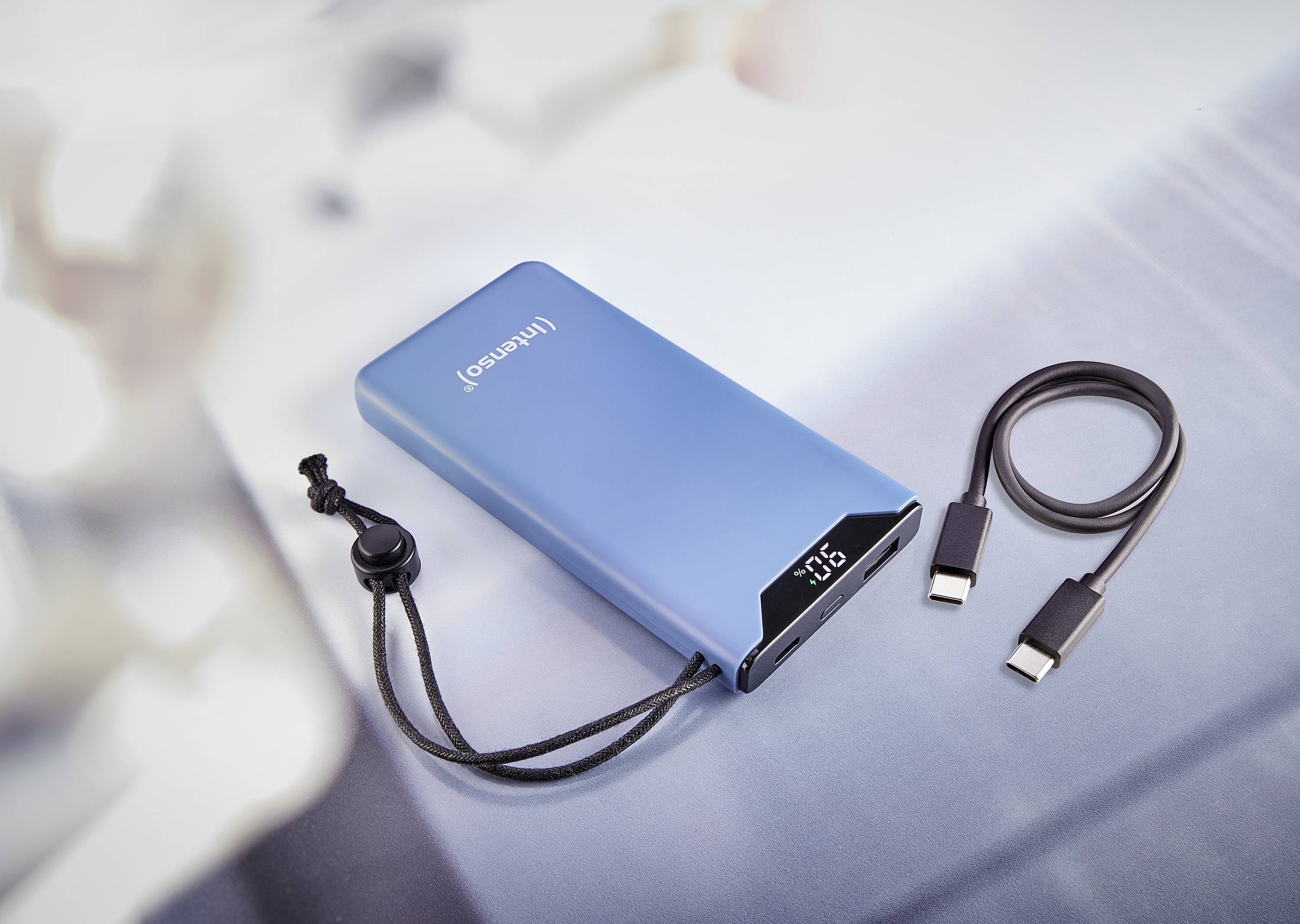 Powerbank blu con display digitale per lo stato di carica, accanto a un cavo di ricarica USB.