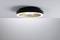 Una moderna lampada da soffitto rotonda con bordo nero e fascio luminoso centrale, installata su un soffitto bianco.