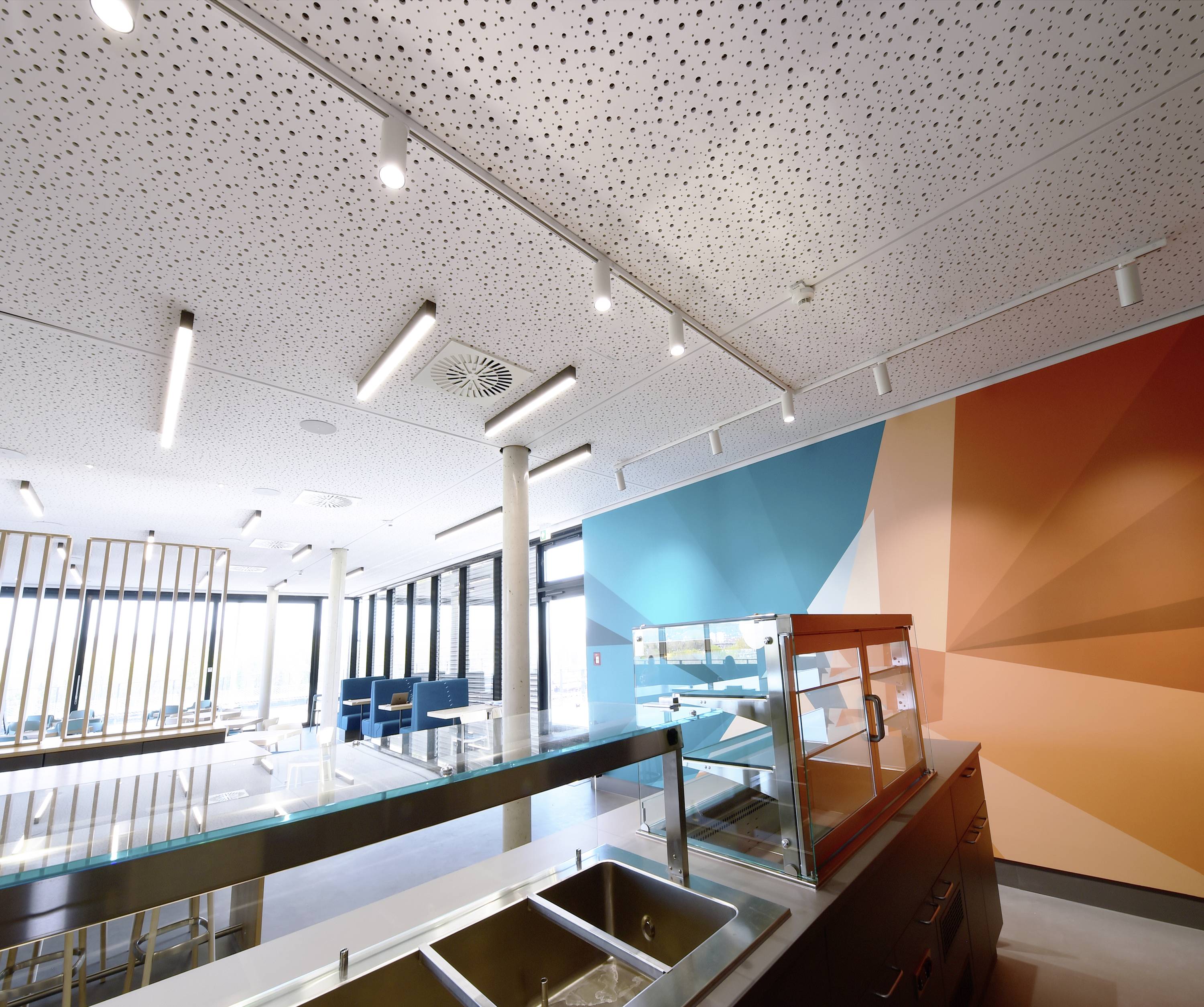 Sala da pranzo moderna con design pulito e minimalista. L'illuminazione luminosa, le pareti colorate e i banconi vuoti sottolineano il concetto dello spazio.