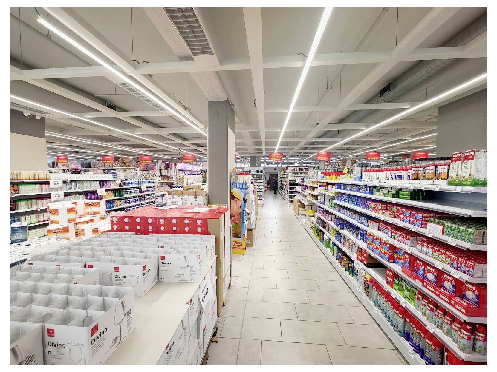 Corsia di supermercato con scaffali di prodotti confezionati e un espositore di merce in scatola in primo piano.