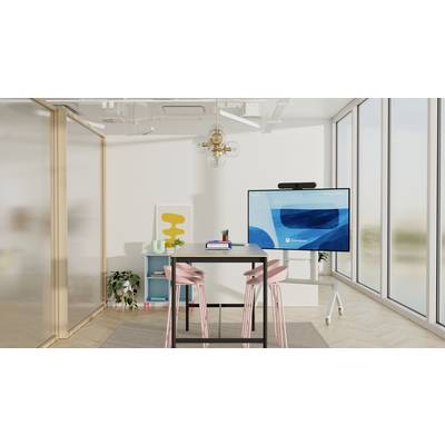 Sala conferenze moderna con un tavolo e sedie, un grande schermo, piante e decorazioni, che mostra un'atmosfera di lavoro accogliente.