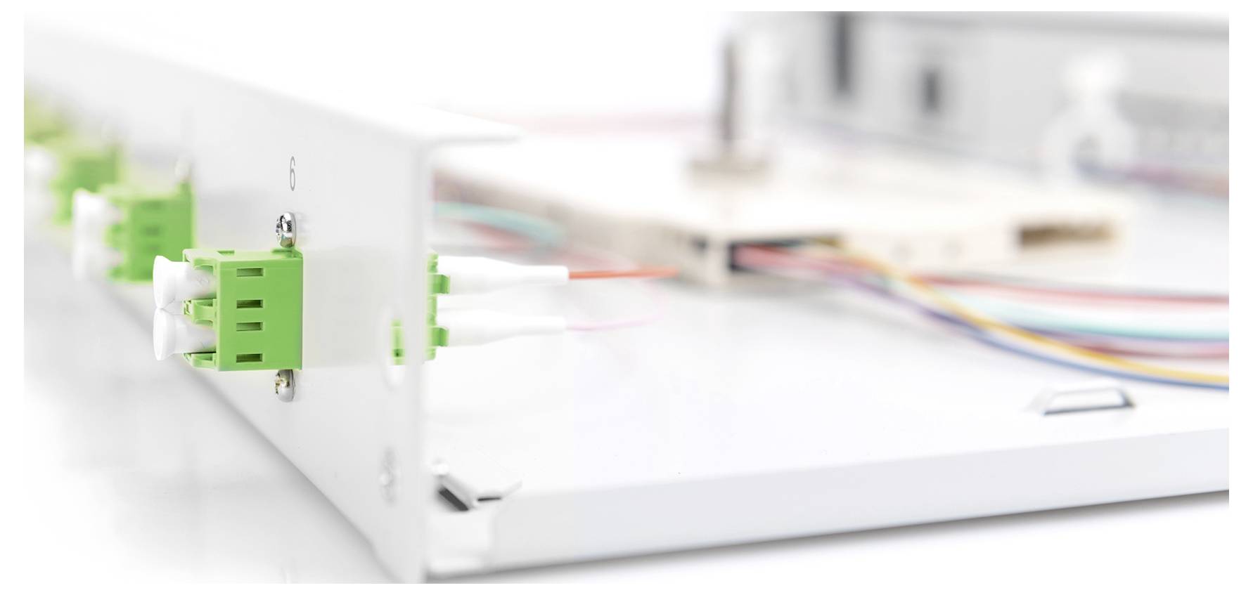 Connettori in fibra ottica su un pannello di gestione cavi bianco, con diversi cavi colorati collegati posteriormente.