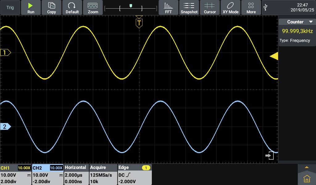 Un oscilloscopio mostra due segnali d'onda in giallo e blu a 99,999 kHz. Gli assi del diagramma sono tensione e tempo.