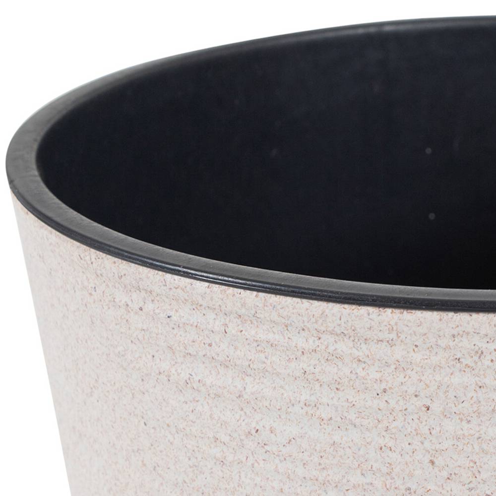 Un cestino rotondo beige con interno nero. Ideale per l'uso in ufficio o a casa.